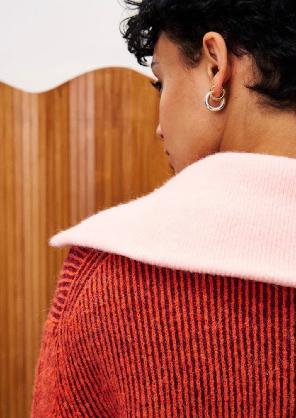 Person wearing a red textured sweater with a white collar.
