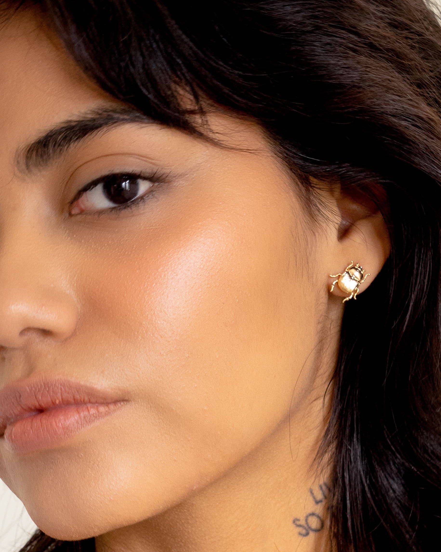 Close-up of a woman wearing a gold earring with a gemstone.