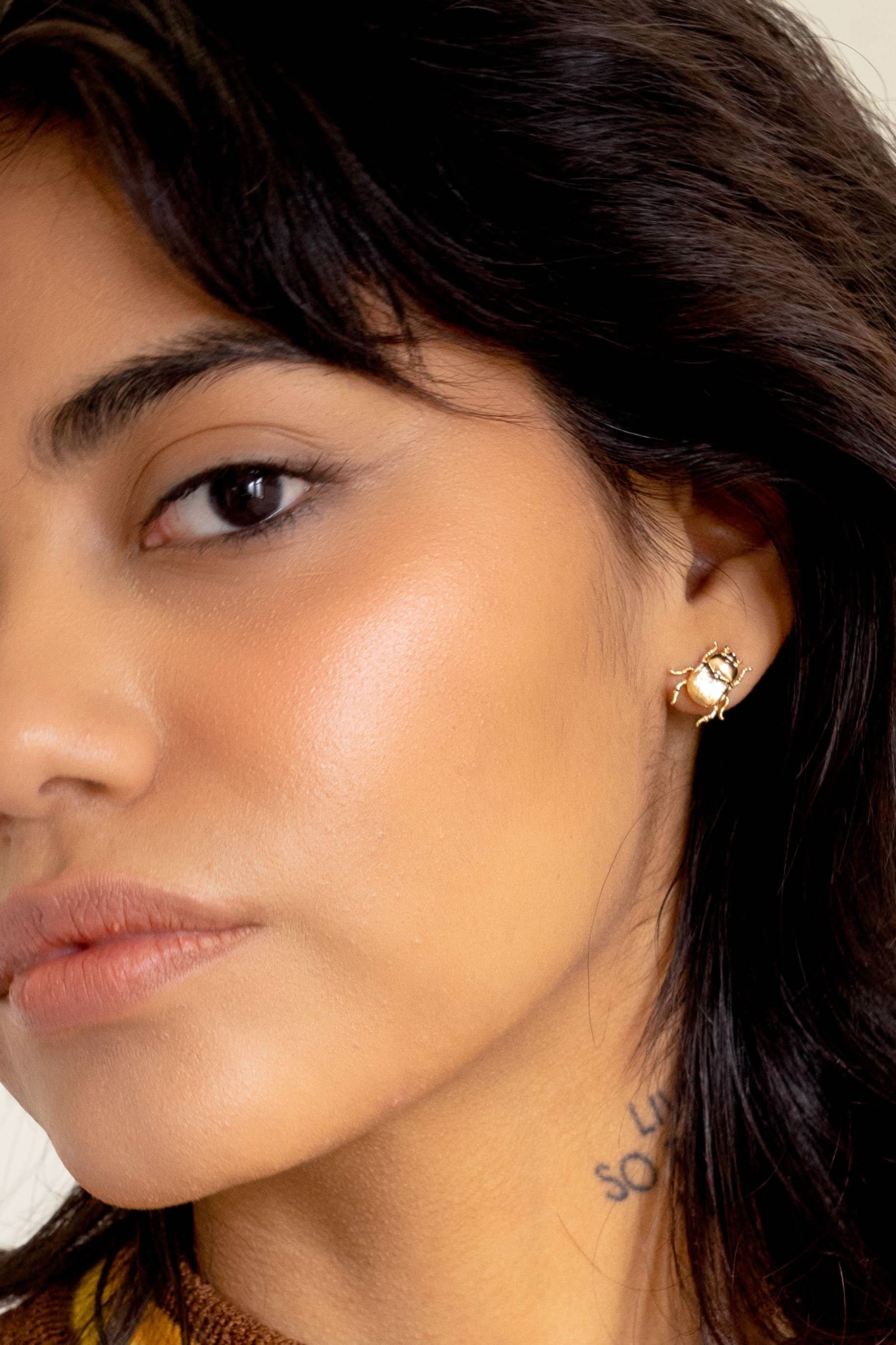 Close-up of a woman wearing a gold earring with a gemstone.