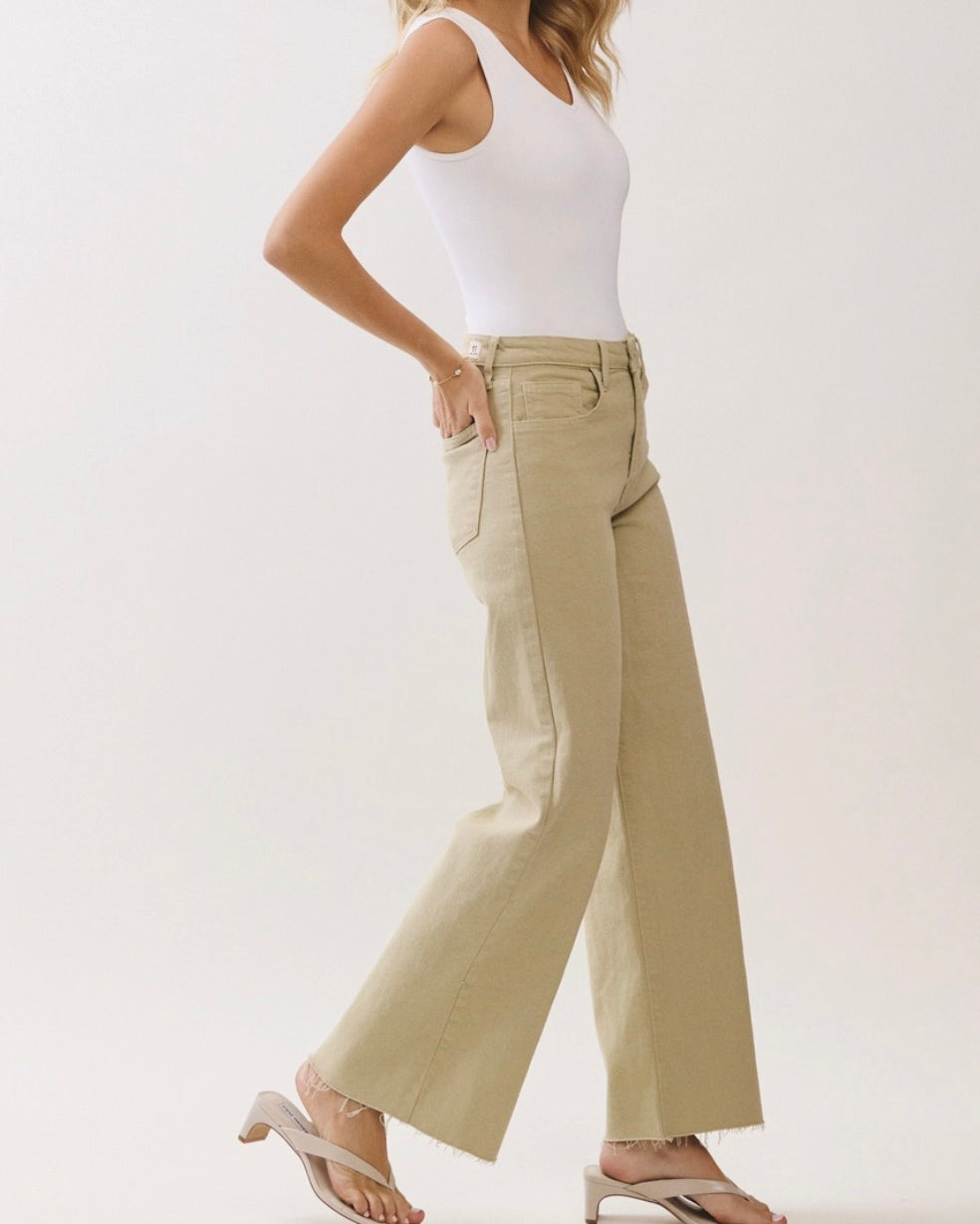 Person wearing beige wide-leg pants and a white top on a plain background