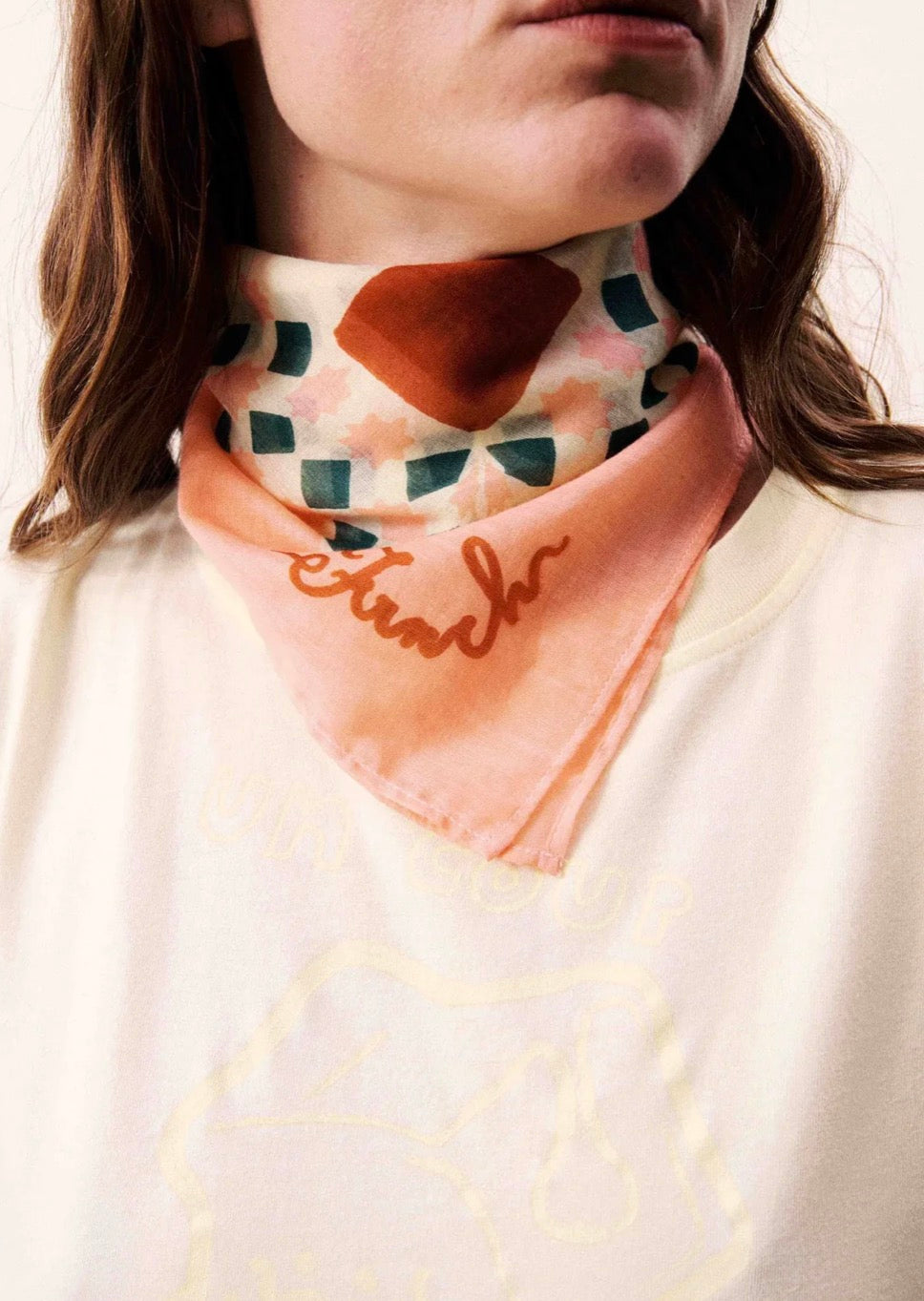 Person wearing a patterned scarf with text on a neutral background