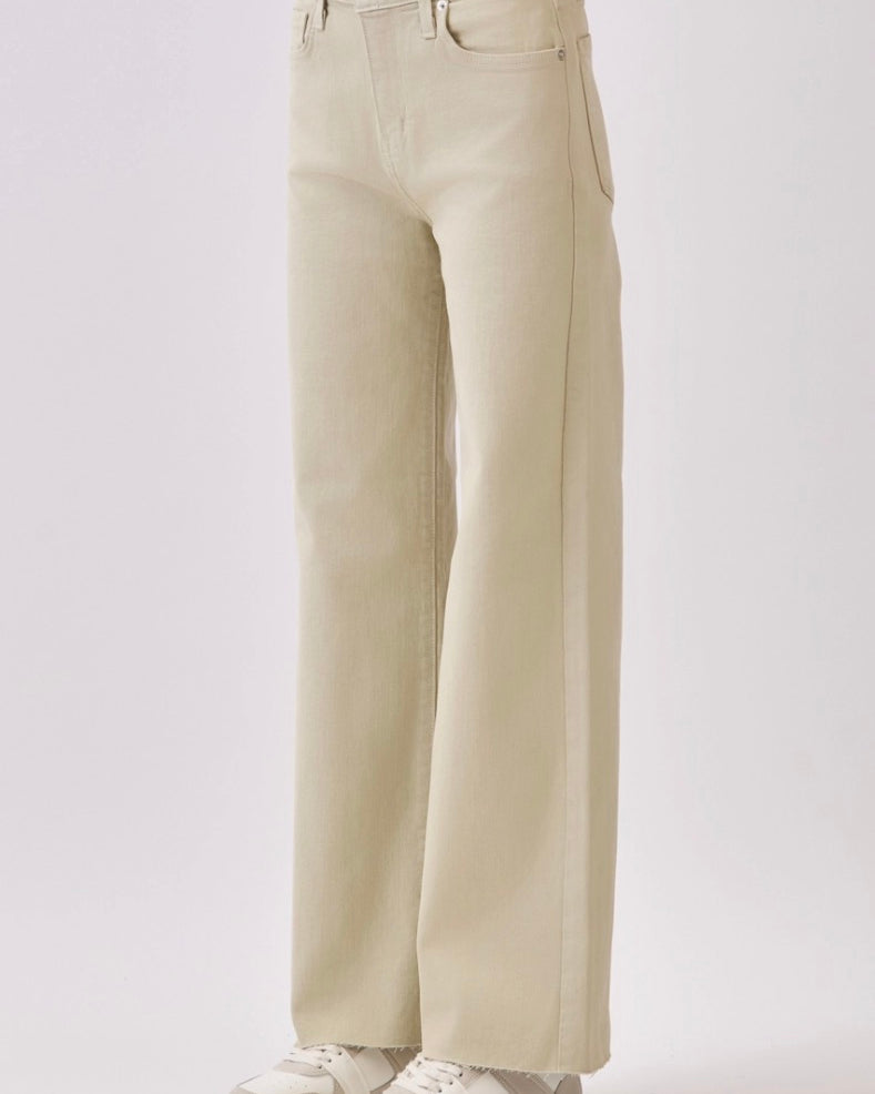 Beige wide-leg jeans worn with white sneakers on a light gray background