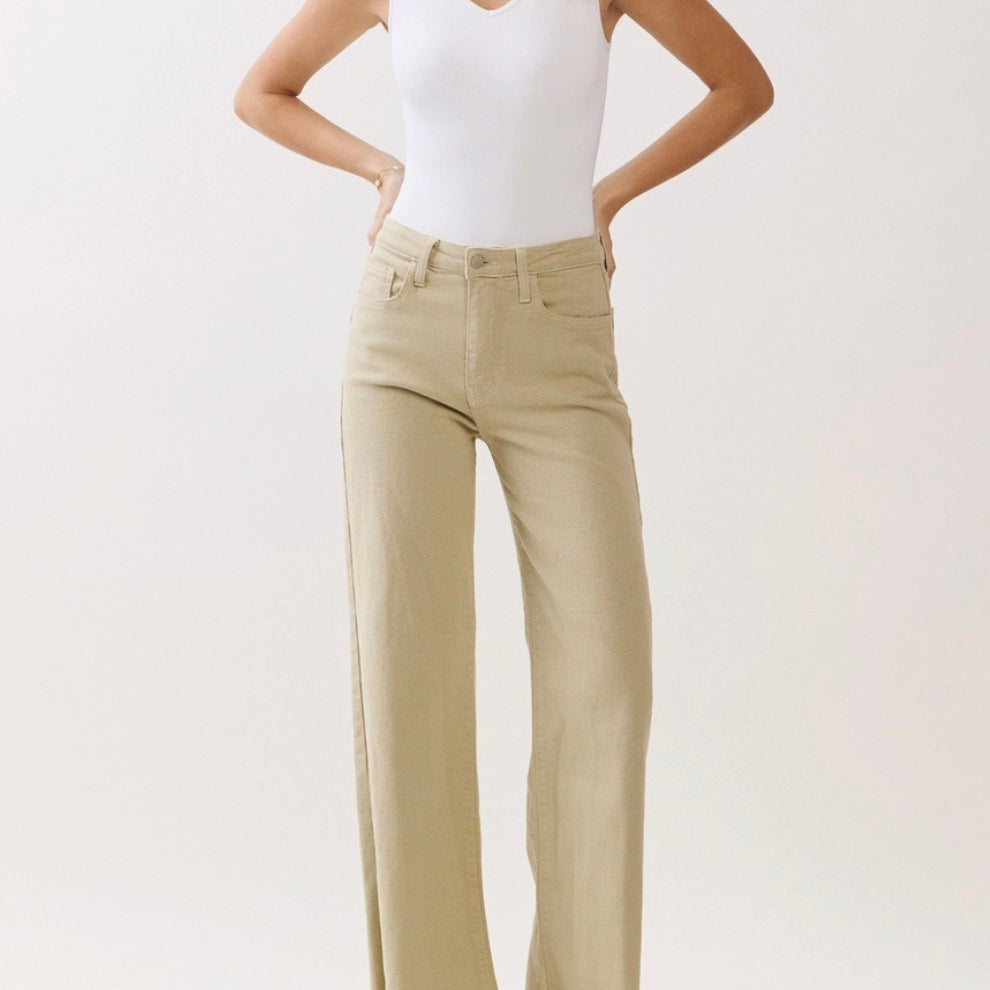 Woman wearing a white tank top and beige wide-leg pants on a light background