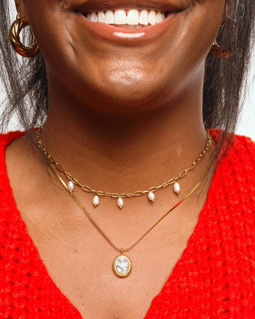 Woman wearing Gold pearl shell necklace with thin herringbone chain