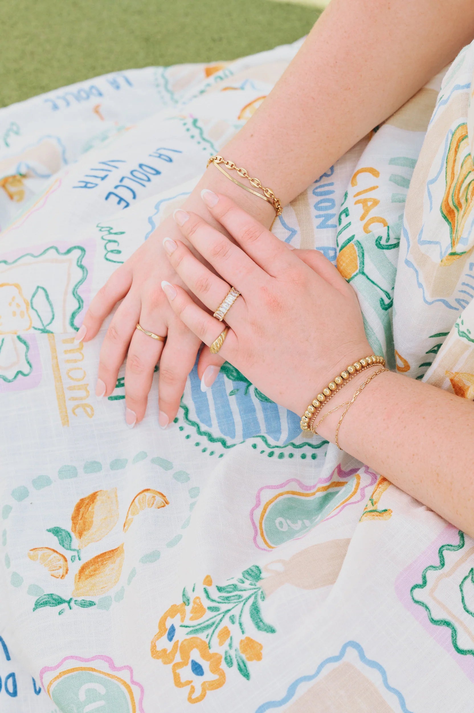 Close-up of hands with rings included golden croissant Ring on a patterned fabric background