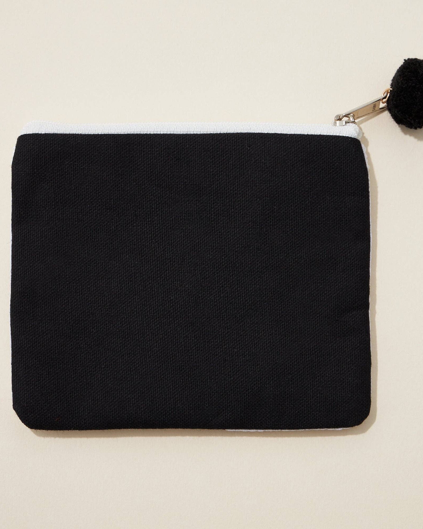 Black pouch with a pom-pom on a beige background