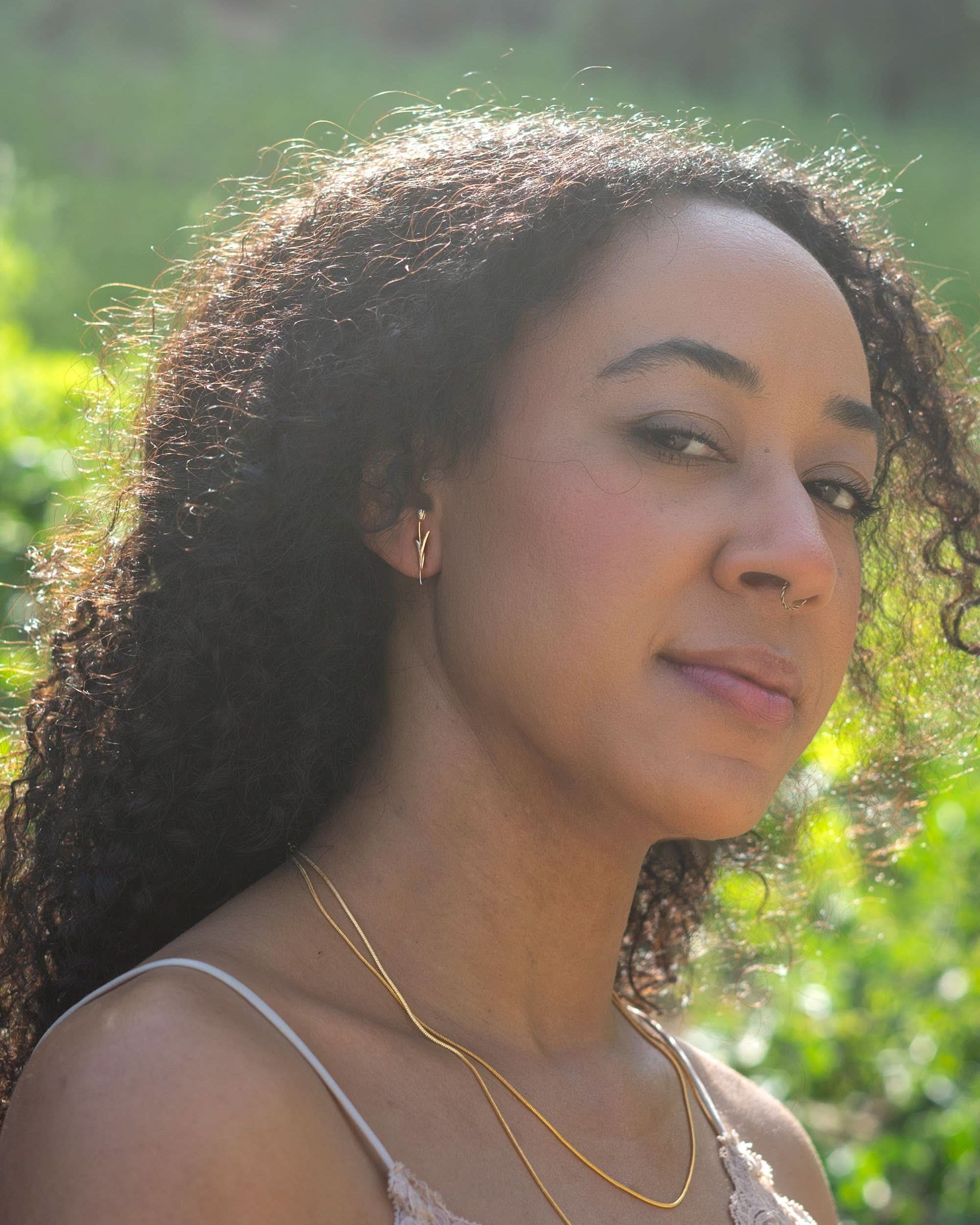Woman with long curly hair and a gold necklace standing outdoors