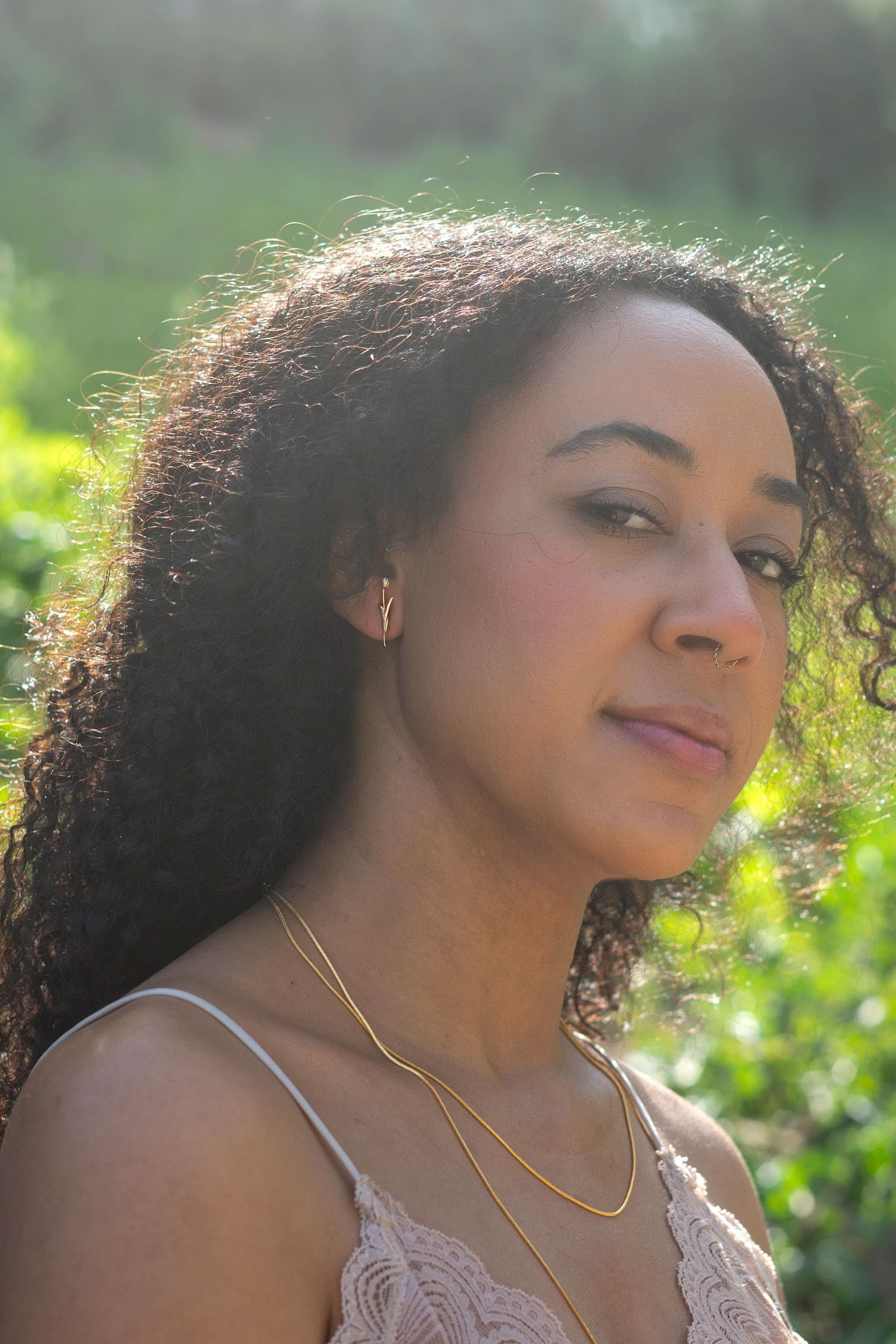 Woman with long curly hair and a gold necklace standing outdoors