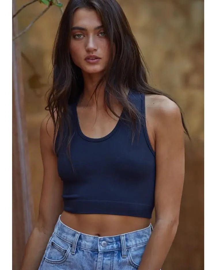 Woman wearing a navy blue knit seamless ribbed scoop with a U-V neckline tank top with light blue jeans.