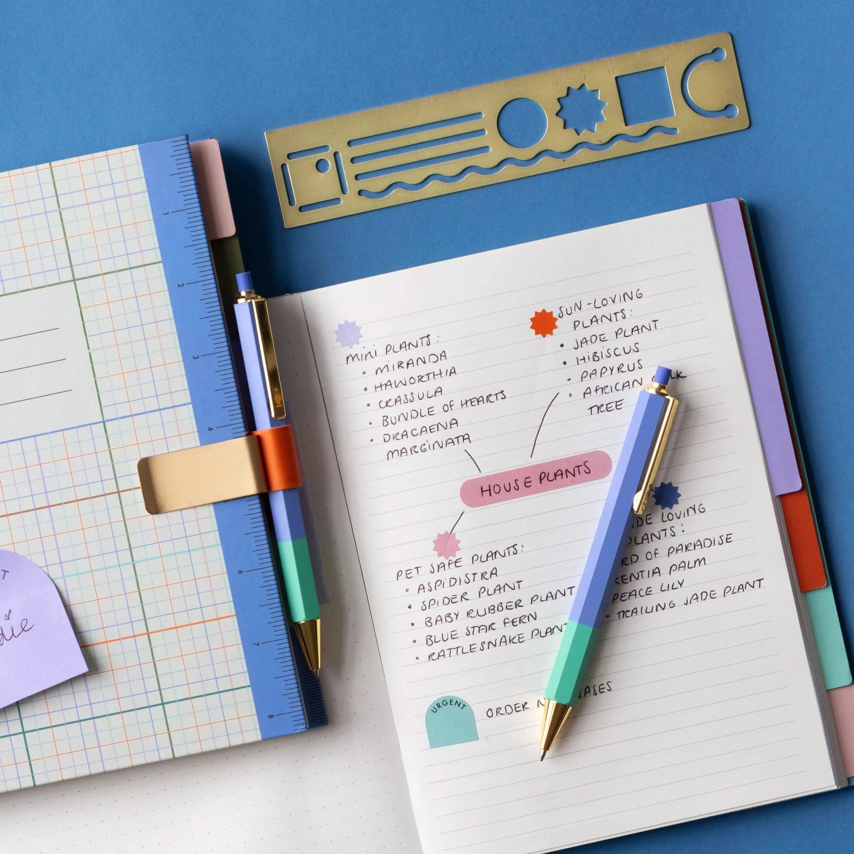 Mechanical pencil and pen in use laying on notebook and in pen holder on blue background