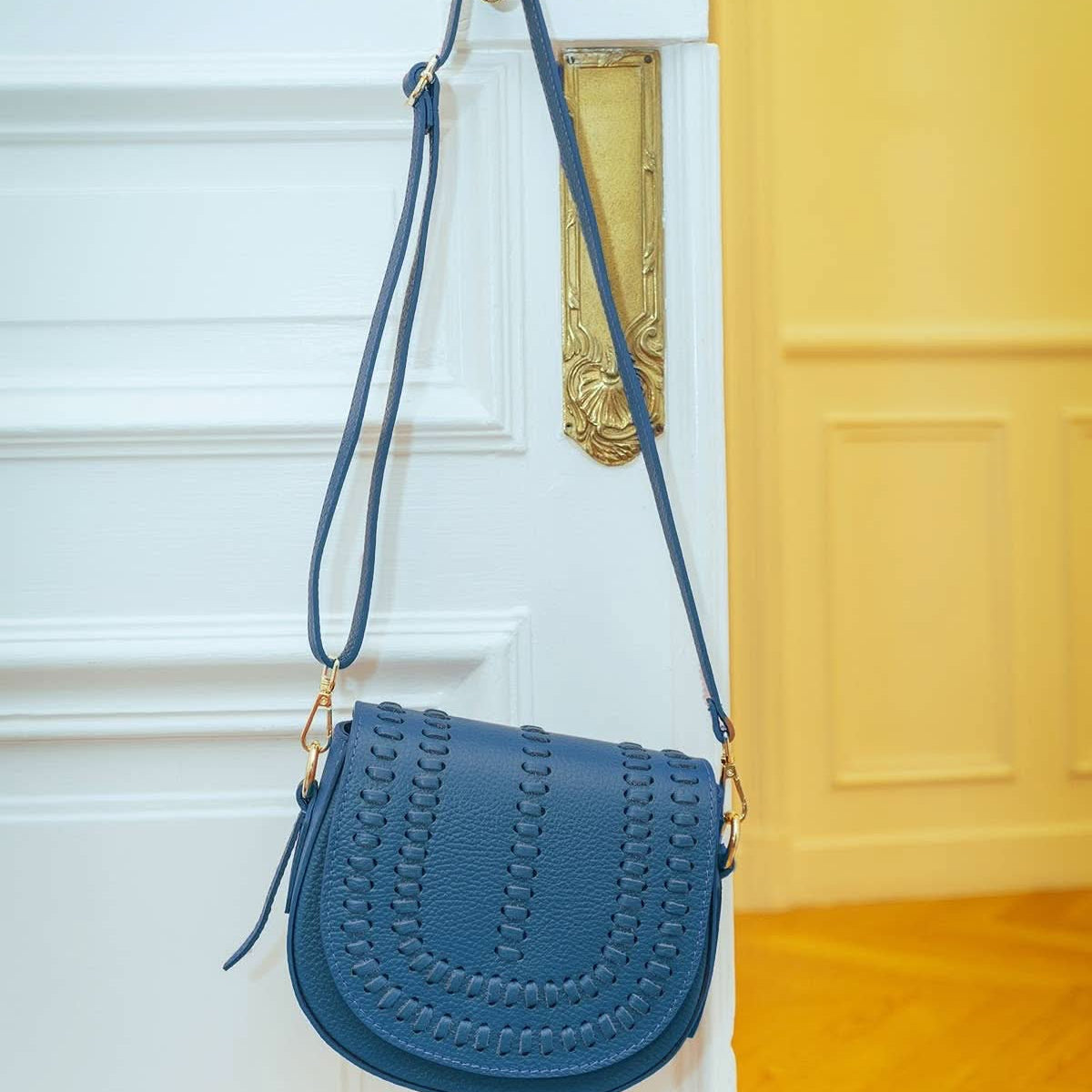 Oil blue colored leather crossbody bag with magnetic front clap and leather woven geometric design and gold Metal details
