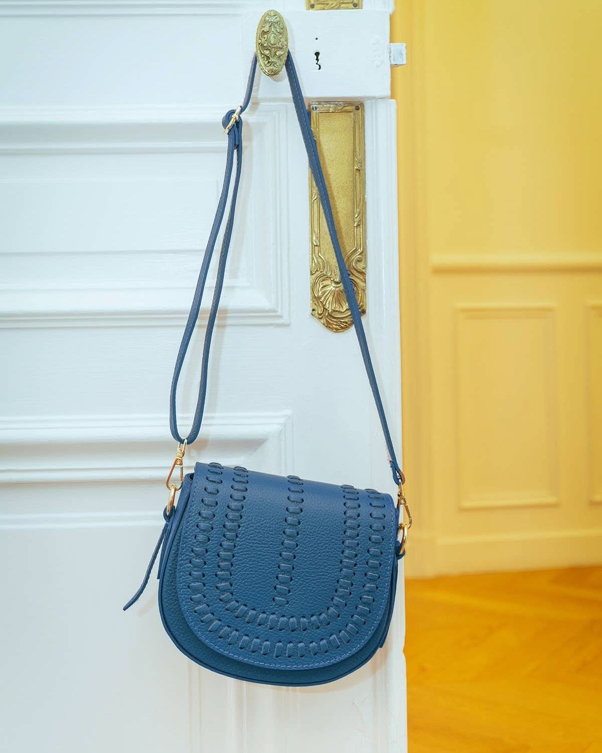 Oil blue colored leather crossbody bag with magnetic front clap and leather woven geometric design and gold Metal details