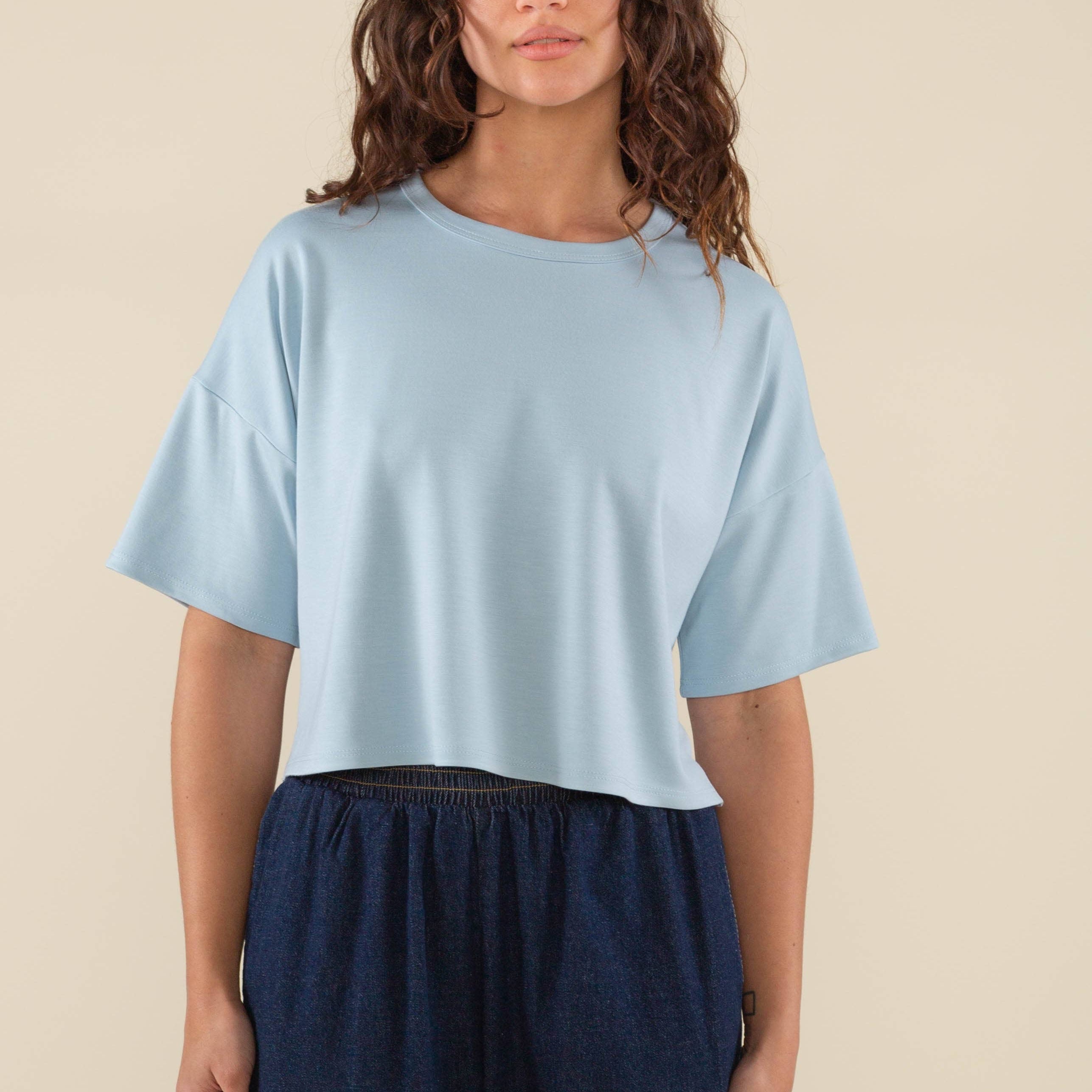Woman wearing light sky blue , short sleeve, jersey, cropped t-shirt and blue jeans
