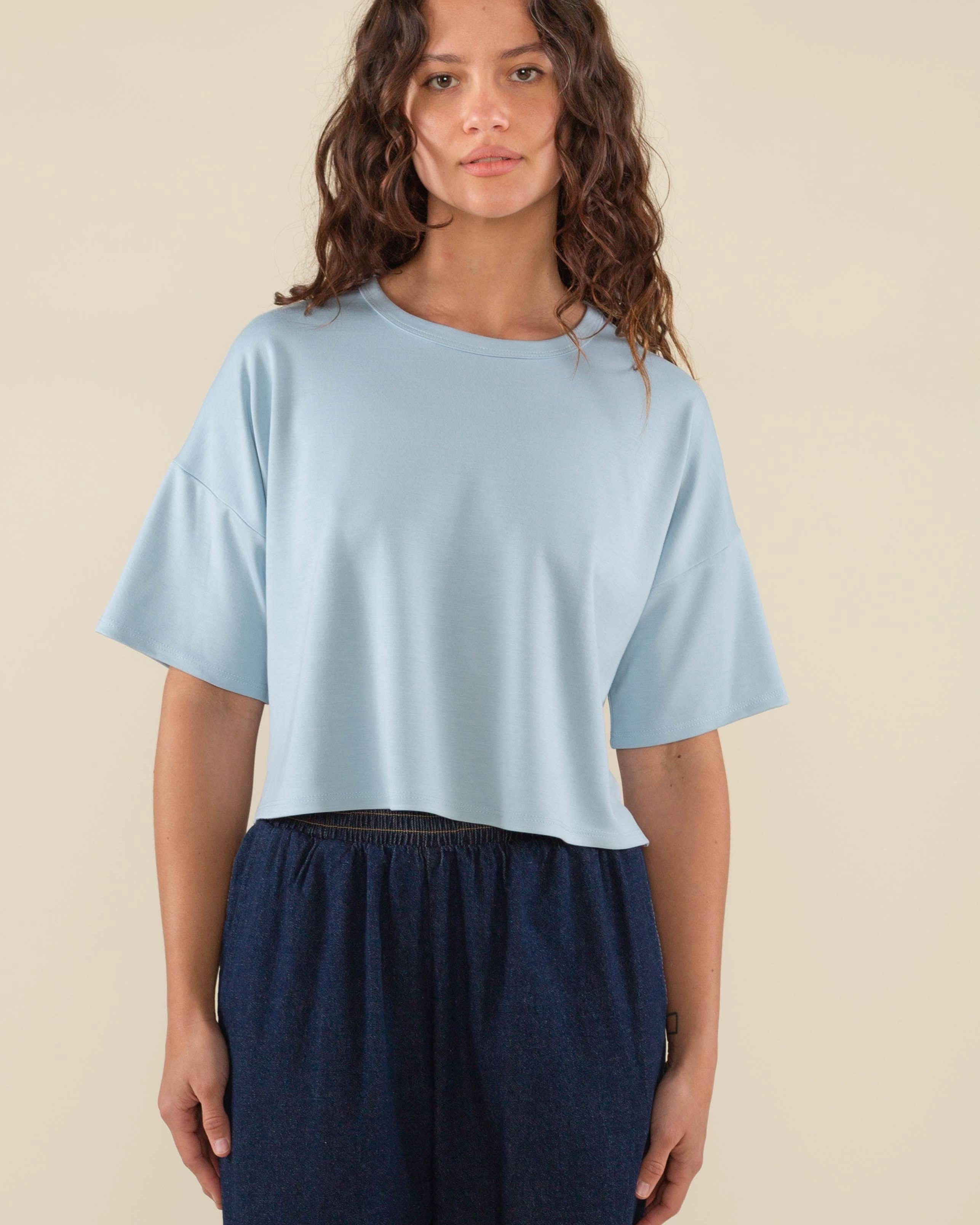 Woman wearing light sky blue , short sleeve, jersey, cropped t-shirt and blue jeans