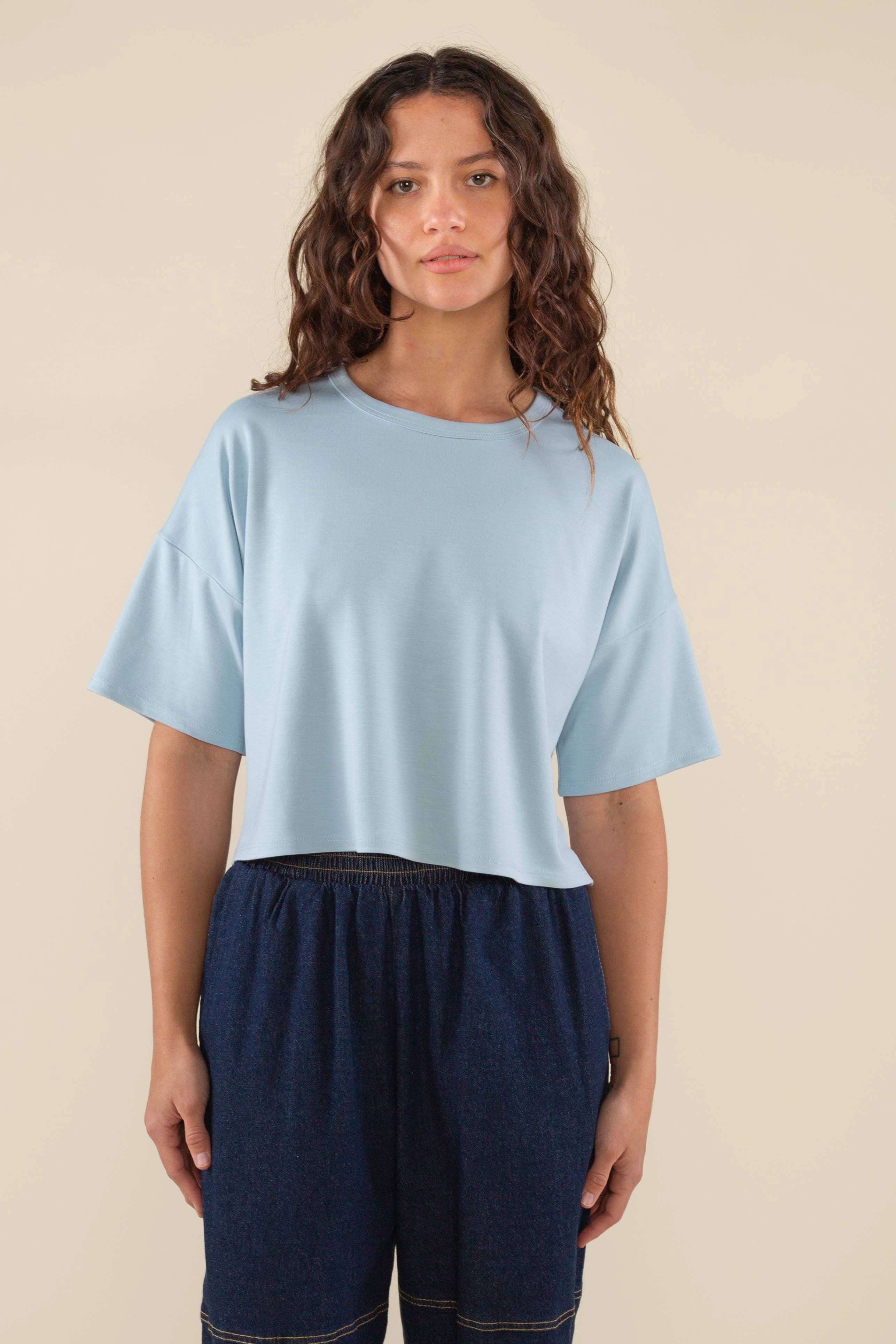 Woman wearing light sky blue , short sleeve, jersey, cropped t-shirt and blue jeans