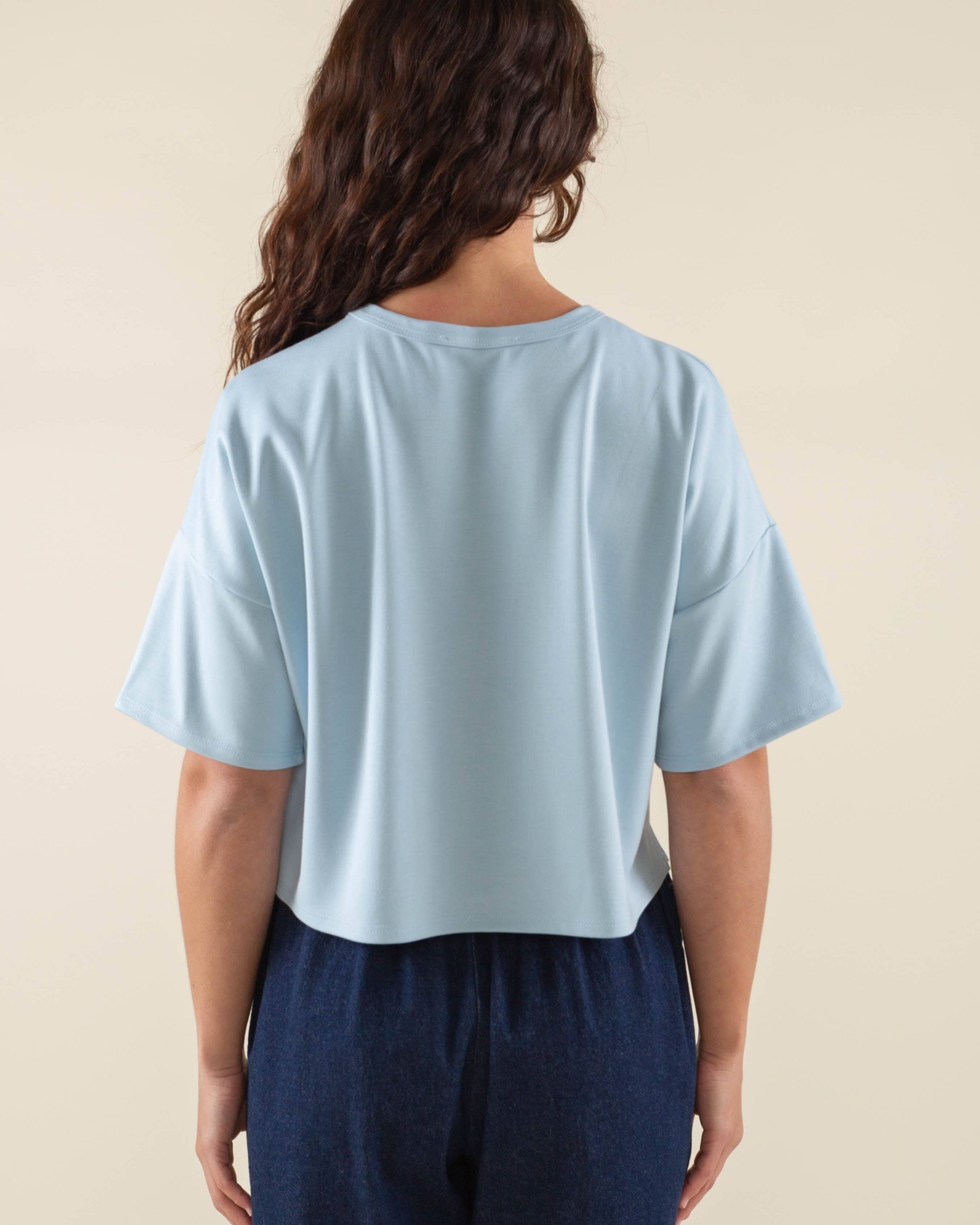 Woman wearing light sky blue, short sleeve, jersey, cropped t-shirt and blue jeans