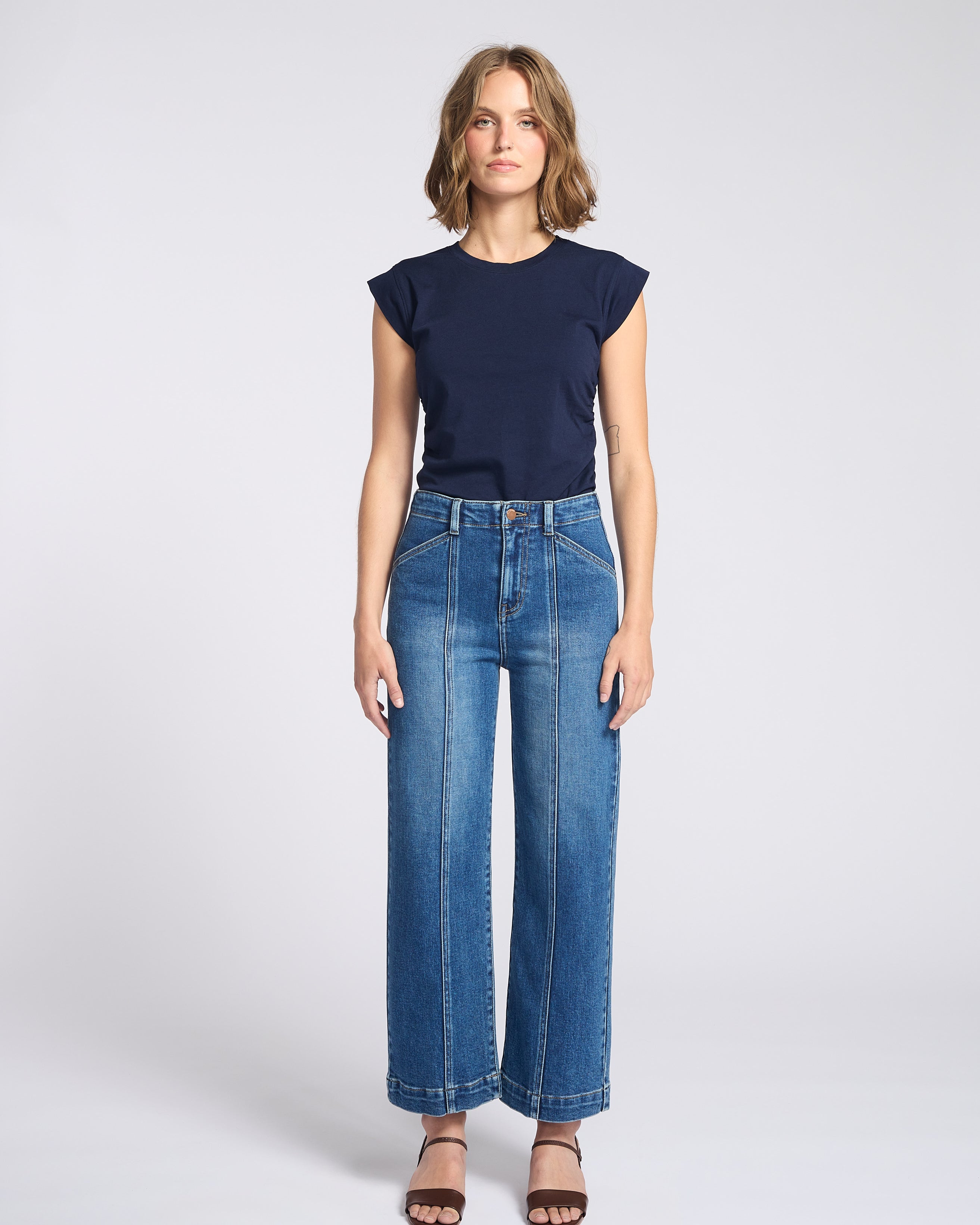 Woman wearing wide legs dark jeans with seam down the front of each pant leg with navy blue shirt
