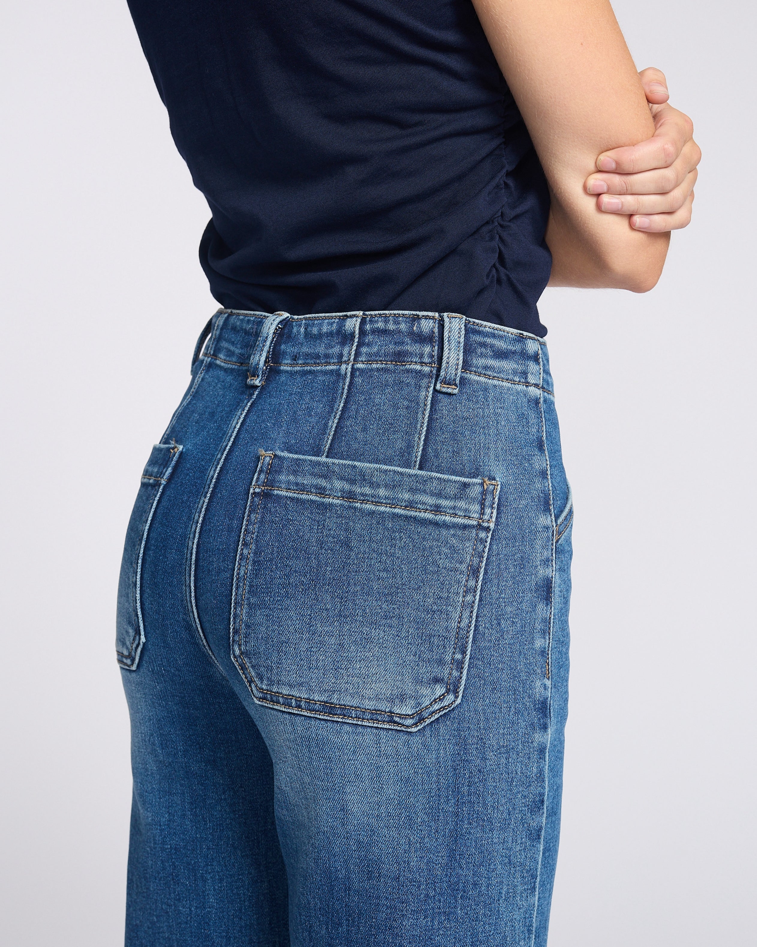 Woman wearing dark wash jean with square pockets with navy blue shirt