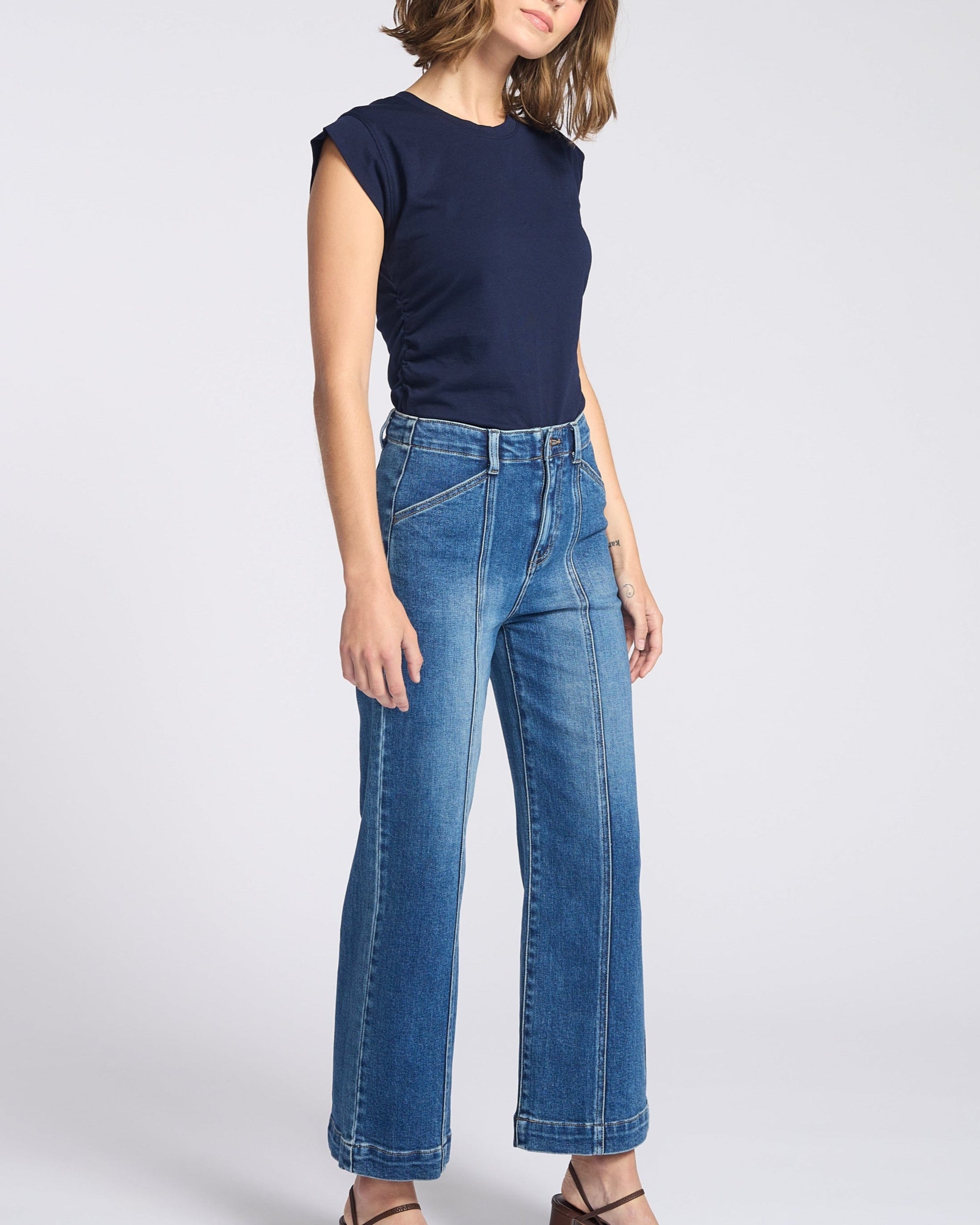 Woman wearing wide legs dark jeans with seam down the front of each pant leg with navy blue shirt