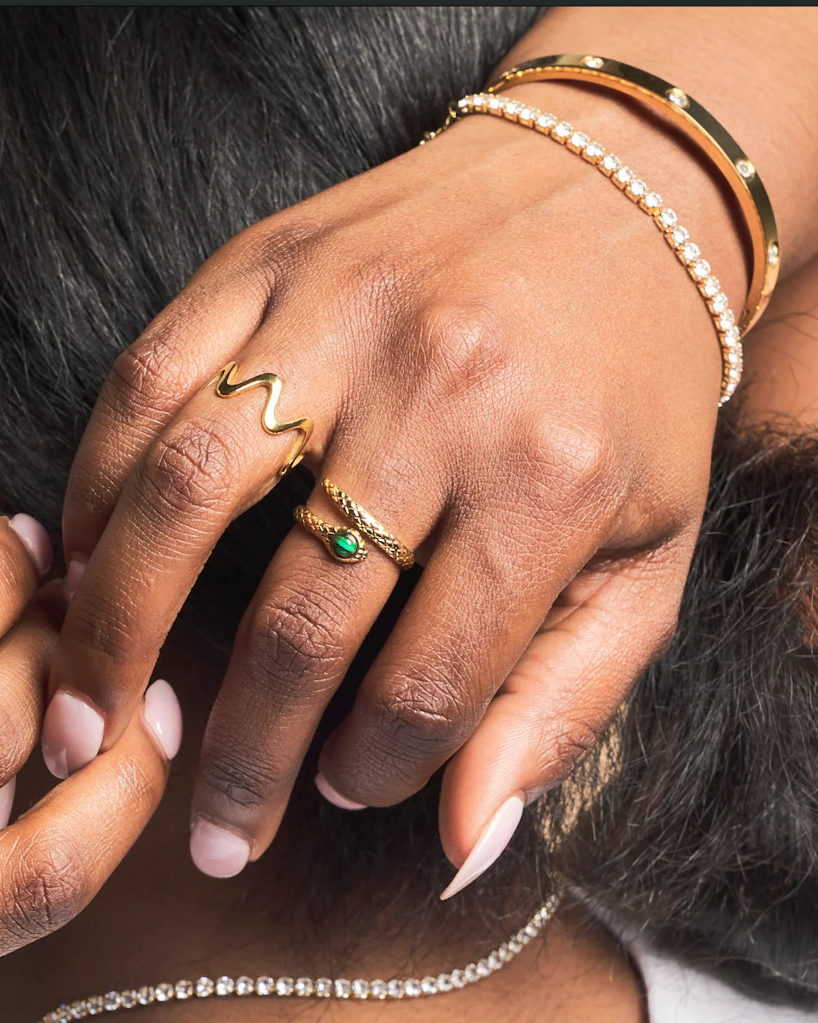 Close-up of hands with gold rings and bracelets on a blurred background