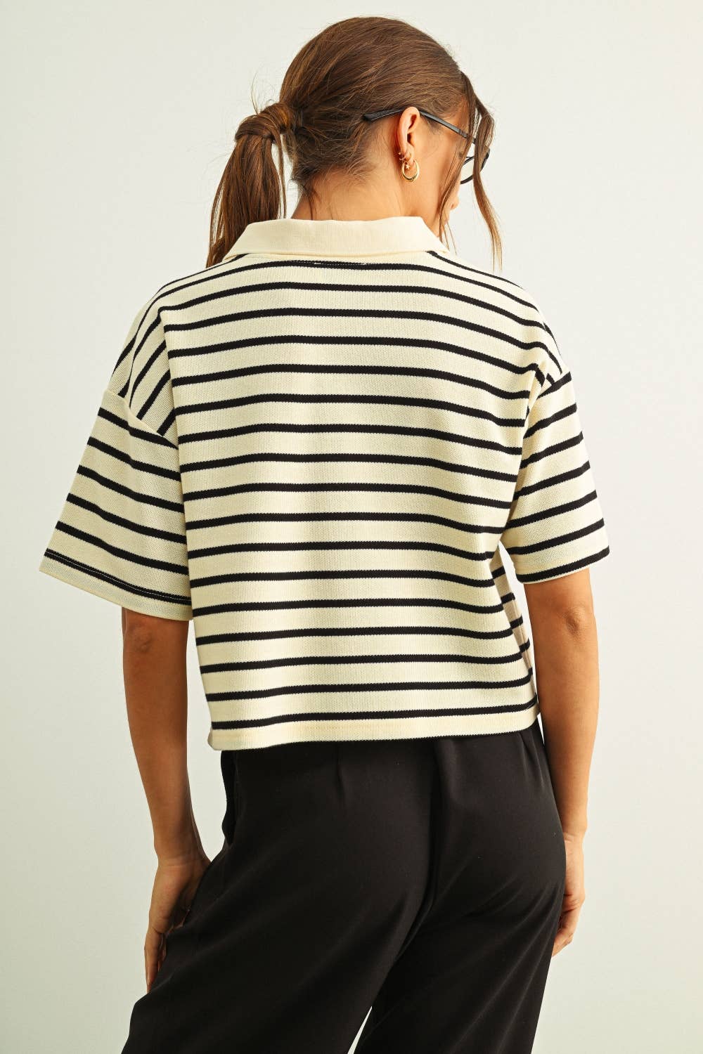 Person wearing a black and white striped shirt with a plain background