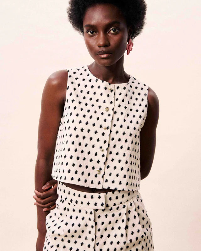Woman wearing a polka dot outfit against a plain background