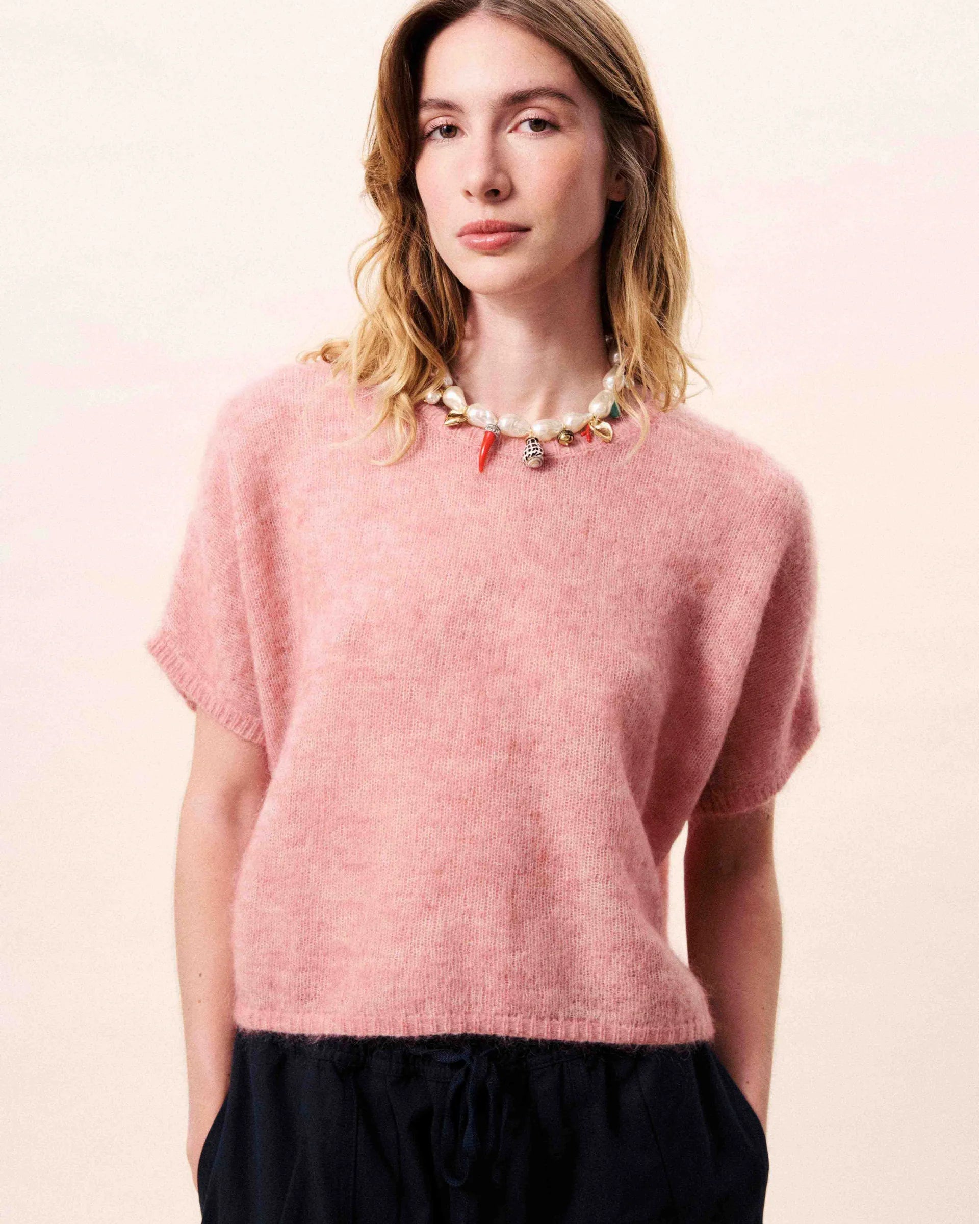 Woman wearing a pink sweater against a light pink background