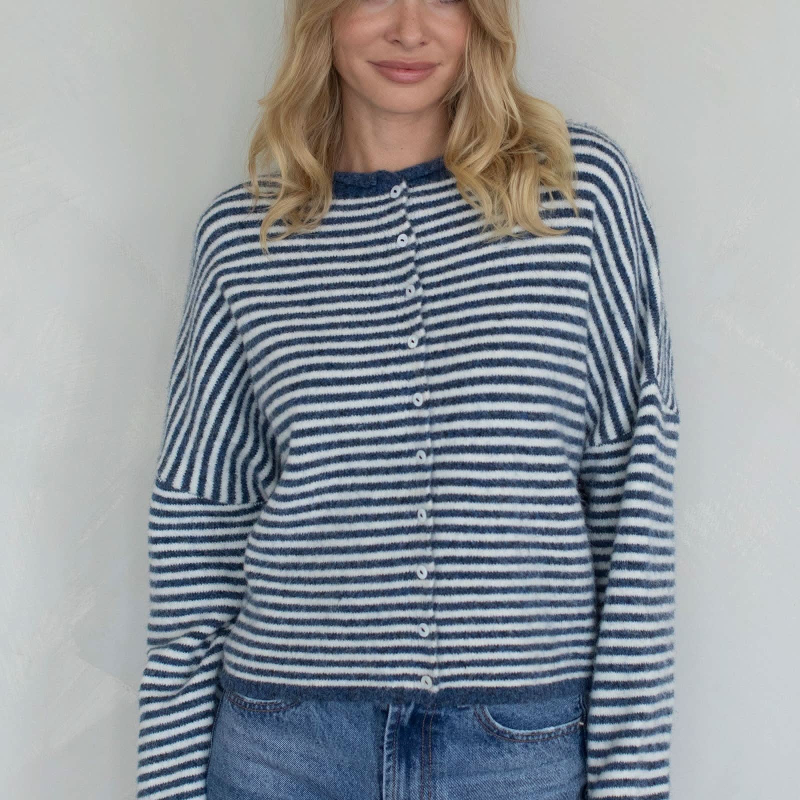 Woman wearing a blue and white striped shirt and jeans against a plain background