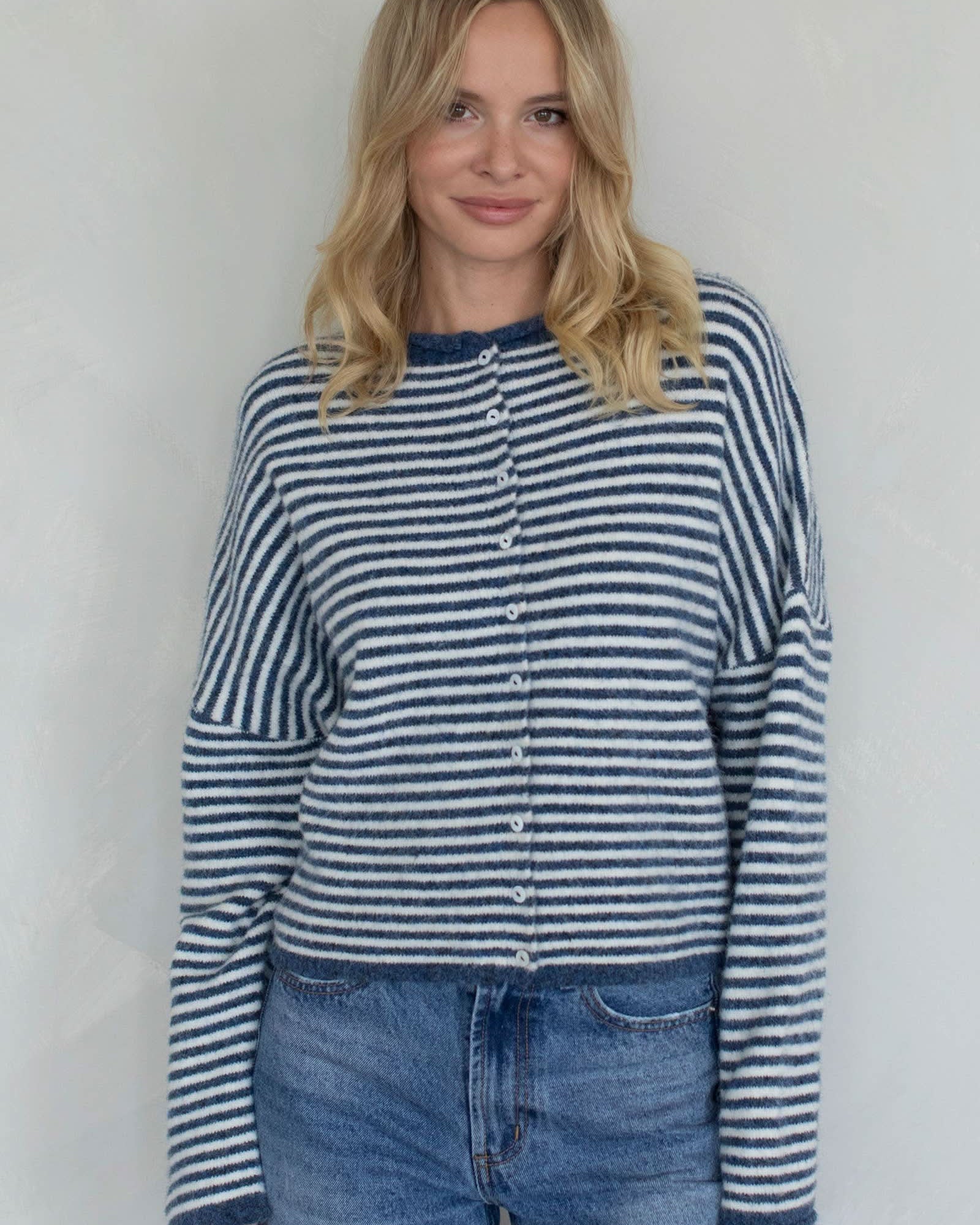 Woman wearing a blue and white striped shirt and jeans against a plain background