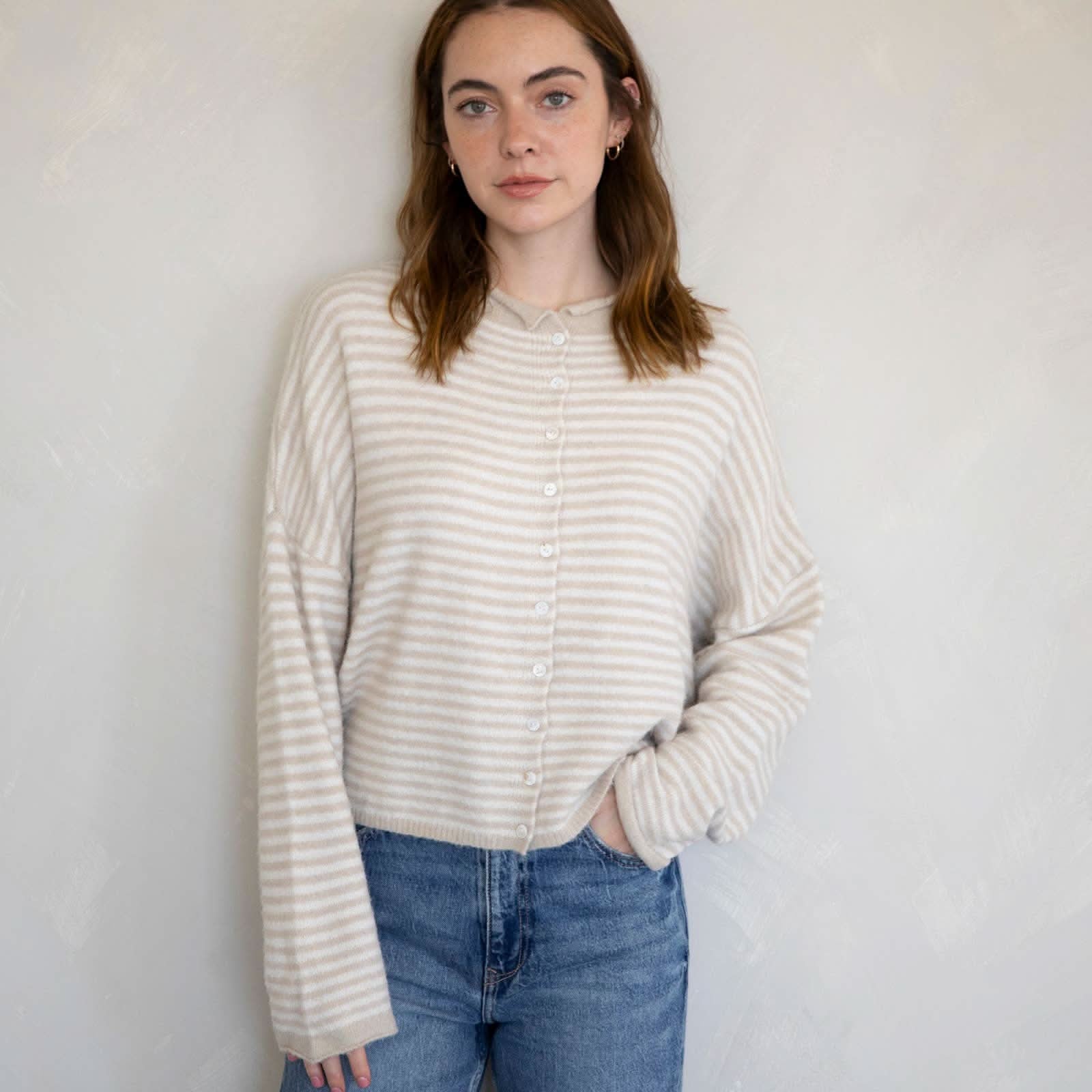 Woman wearing a striped sweater and jeans against a plain background