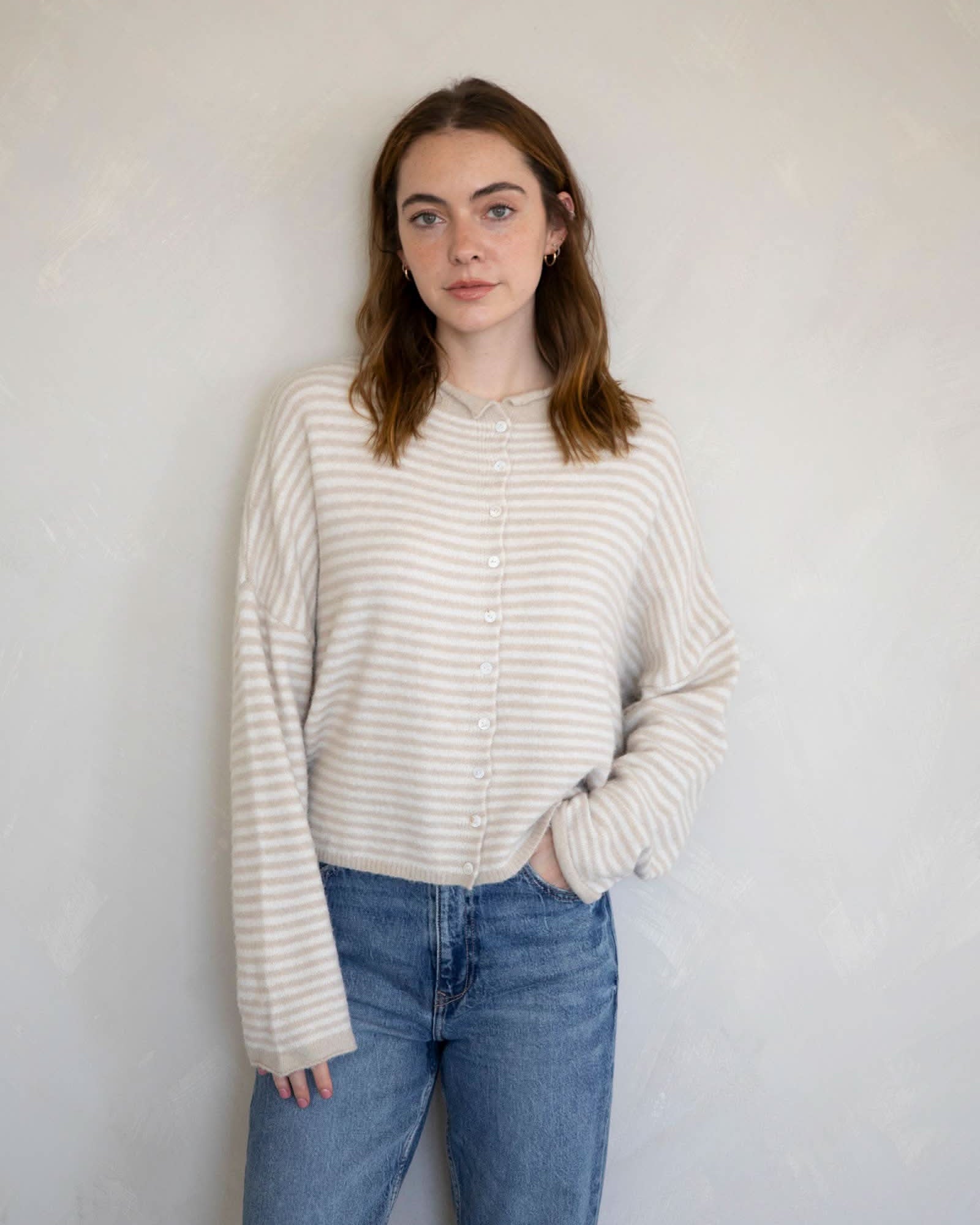 Woman wearing a striped sweater and jeans against a plain background