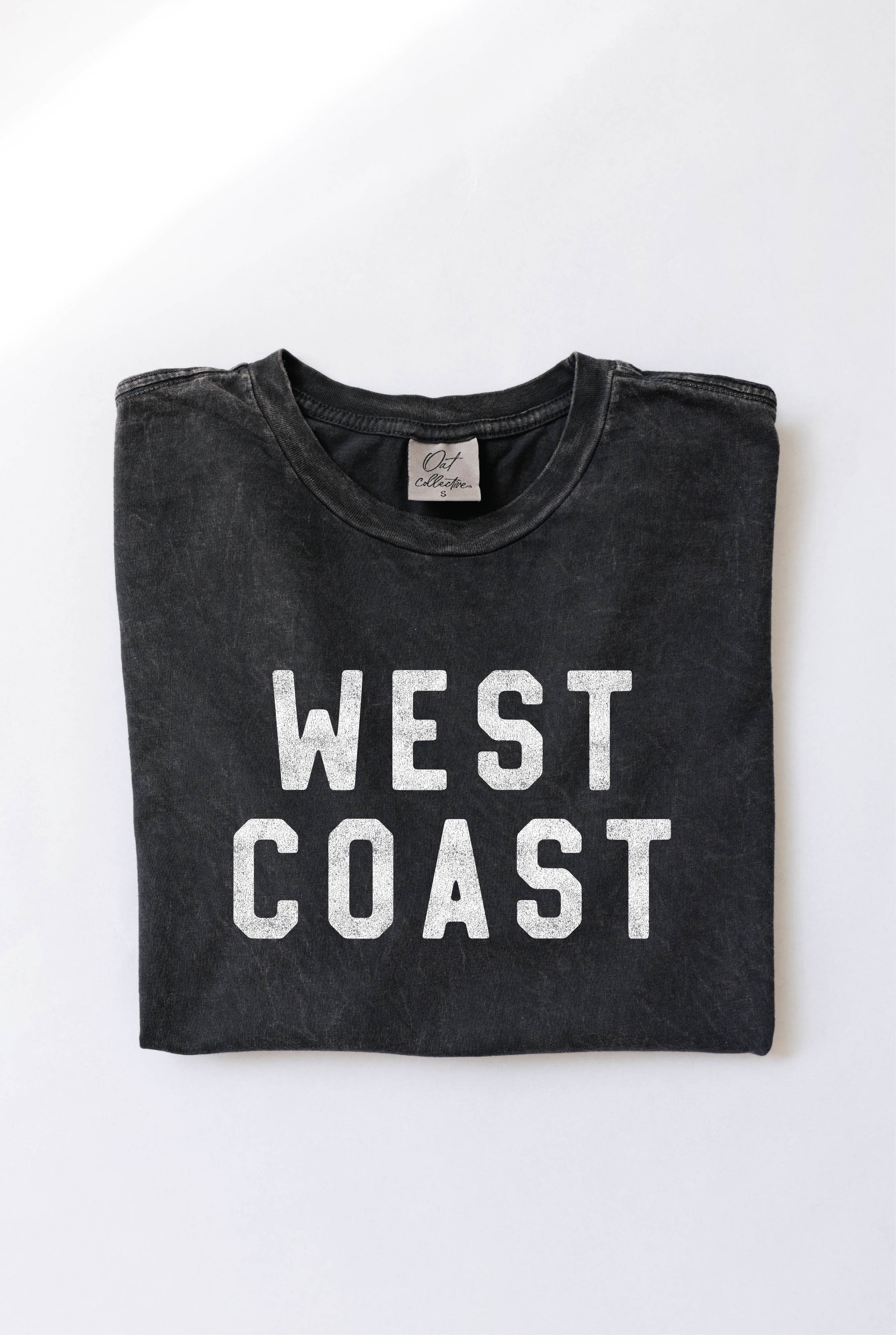 Folded black t-shirt with 'WEST COAST' text on a white background