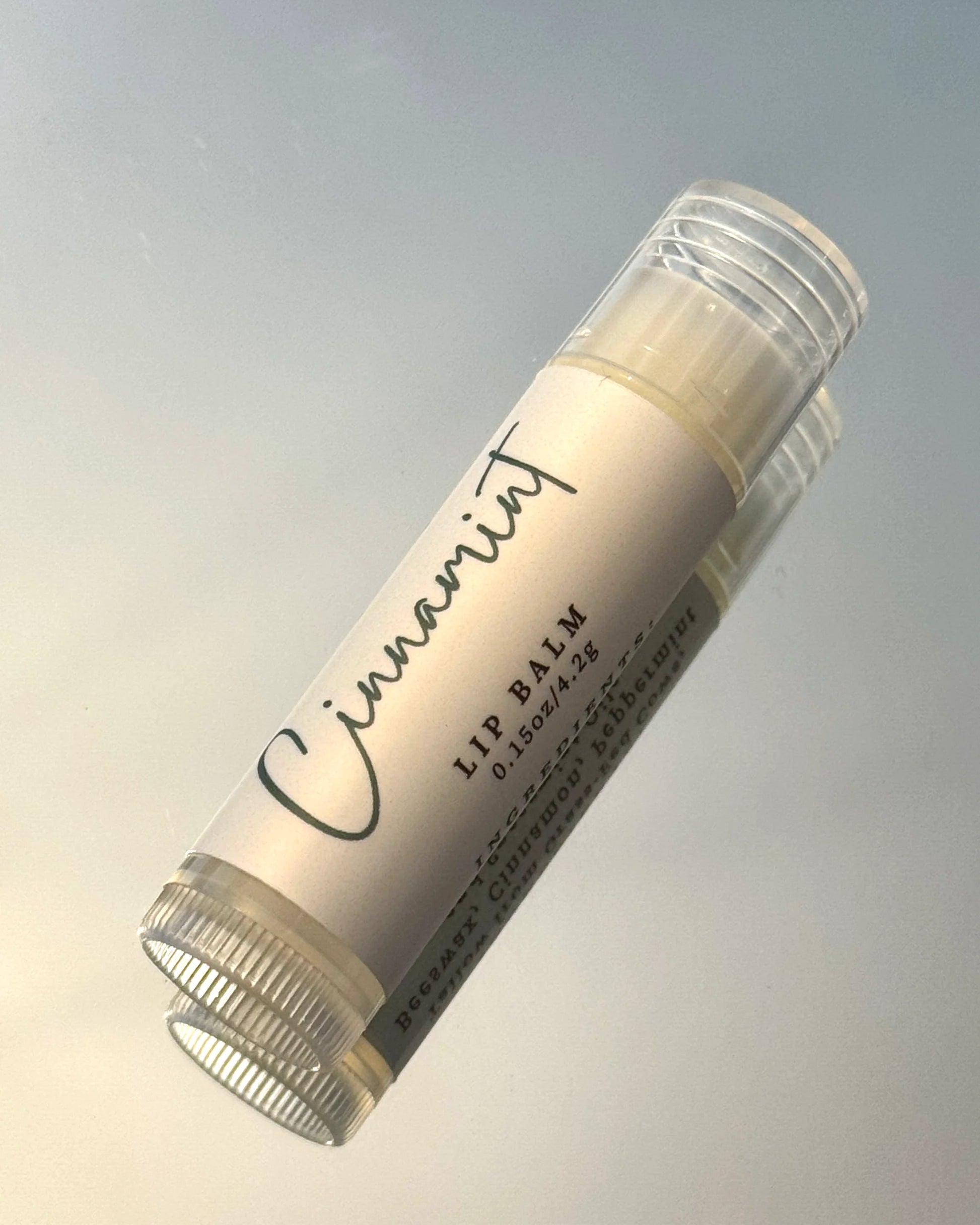 Lip balm stick with 'Cinnamint' branding on a gradient background