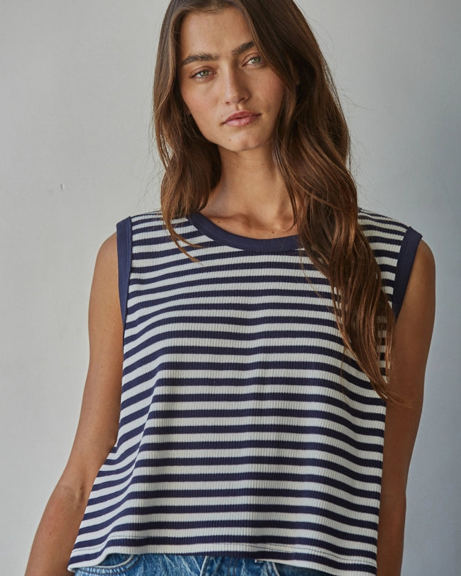 Woman wearing a navy and white striped sleeveless top against a plain background