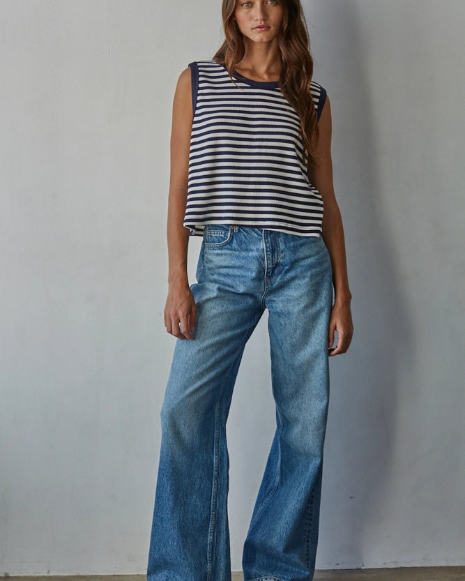 Woman wearing a striped top and blue jeans against a plain background