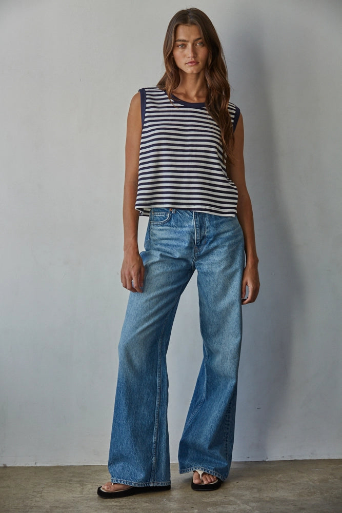 Woman wearing a striped top and blue jeans against a plain background