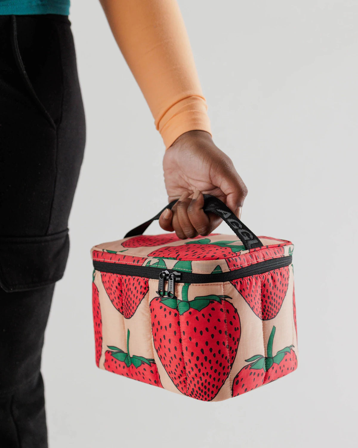 Person holding a strawberry-patterned cooler bag against a plain background