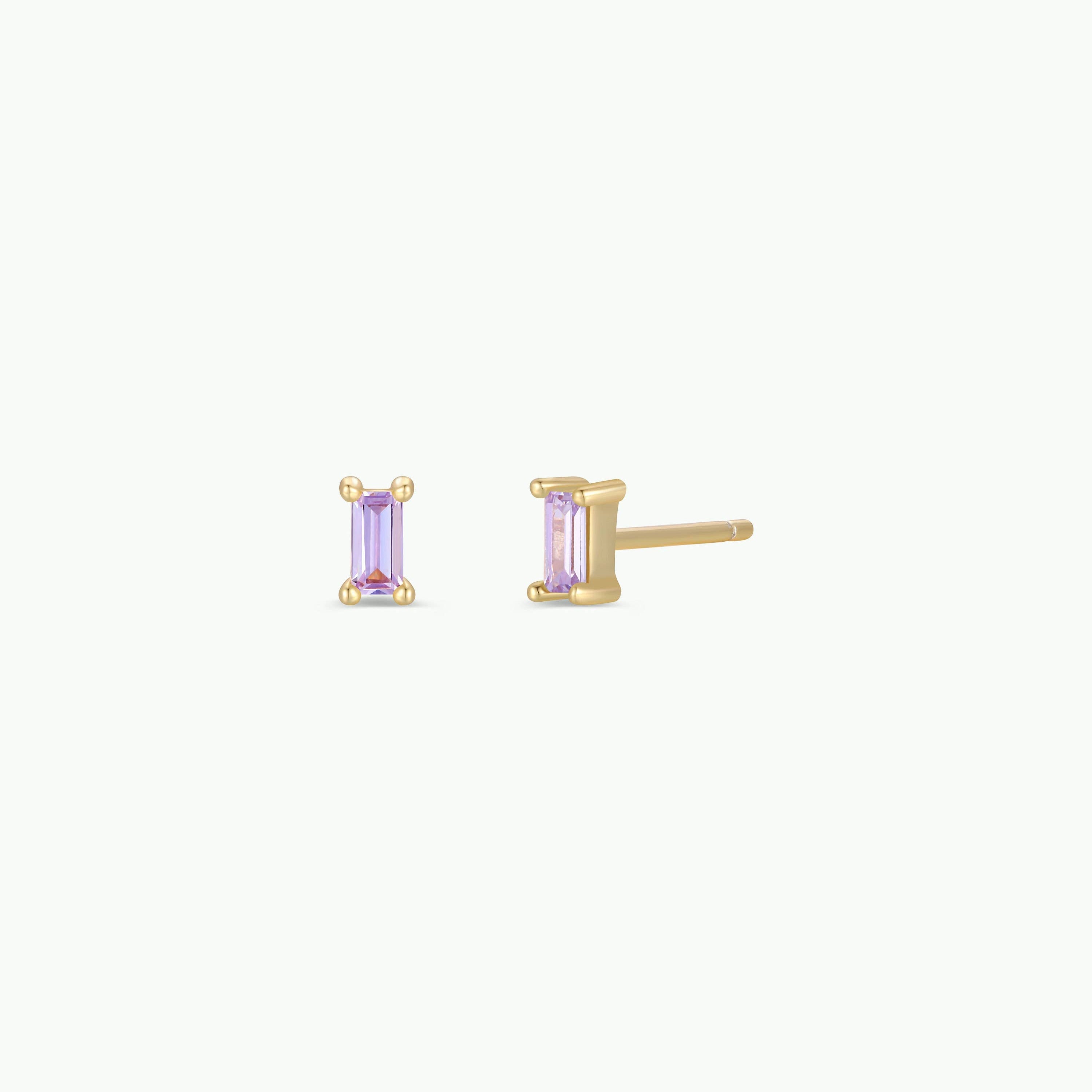 Gold earrings with purple gemstones on a white background