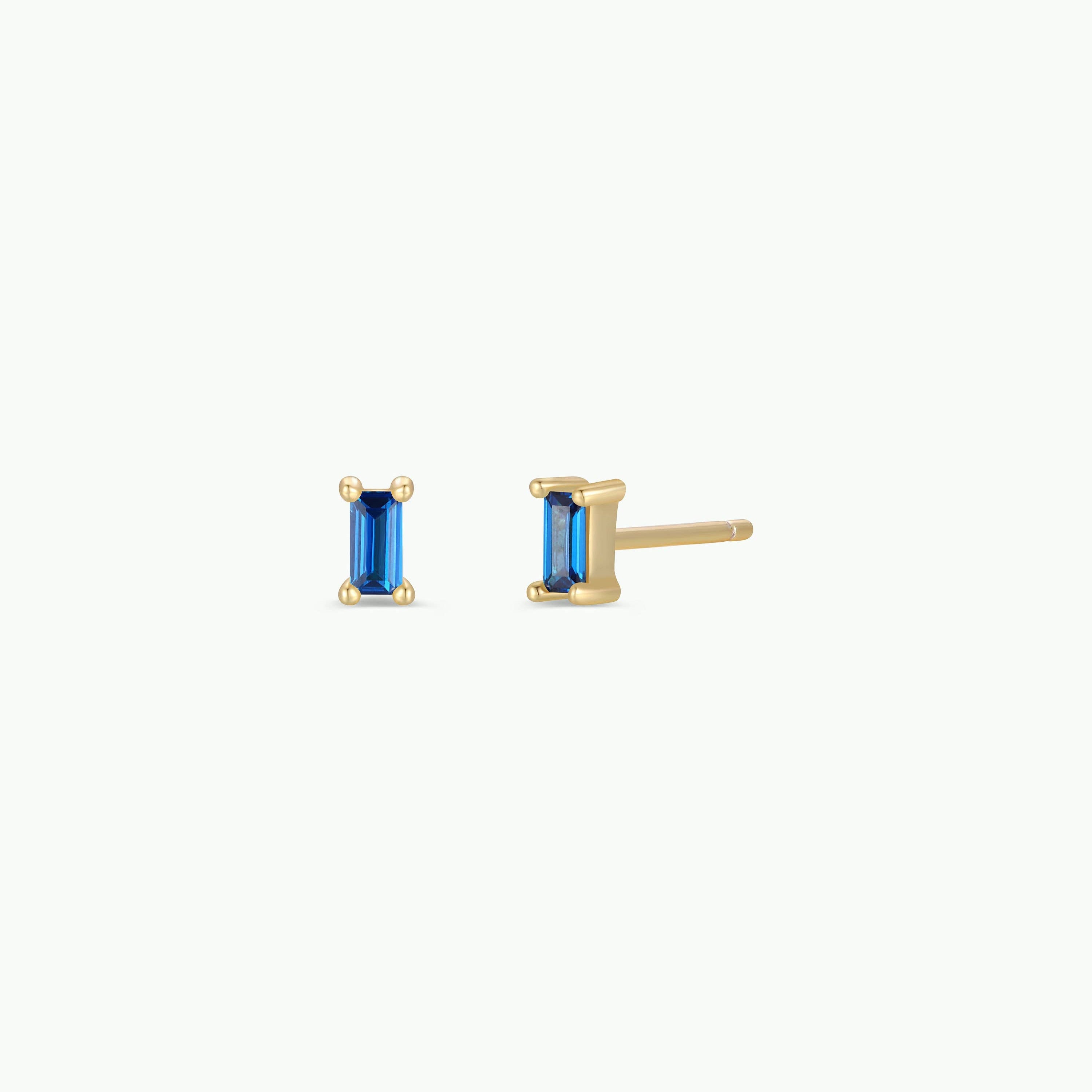 Gold earrings with blue gemstones on a white background