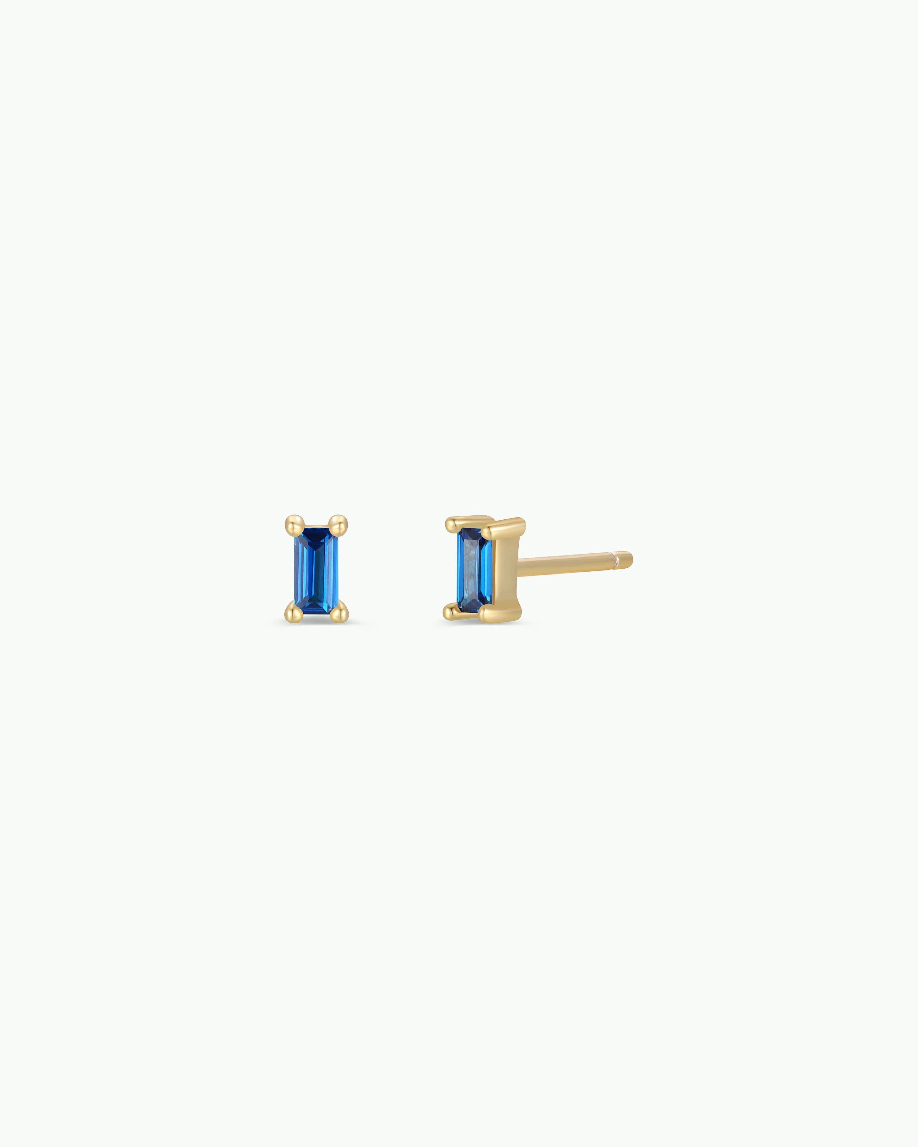 Gold earrings with blue gemstones on a white background