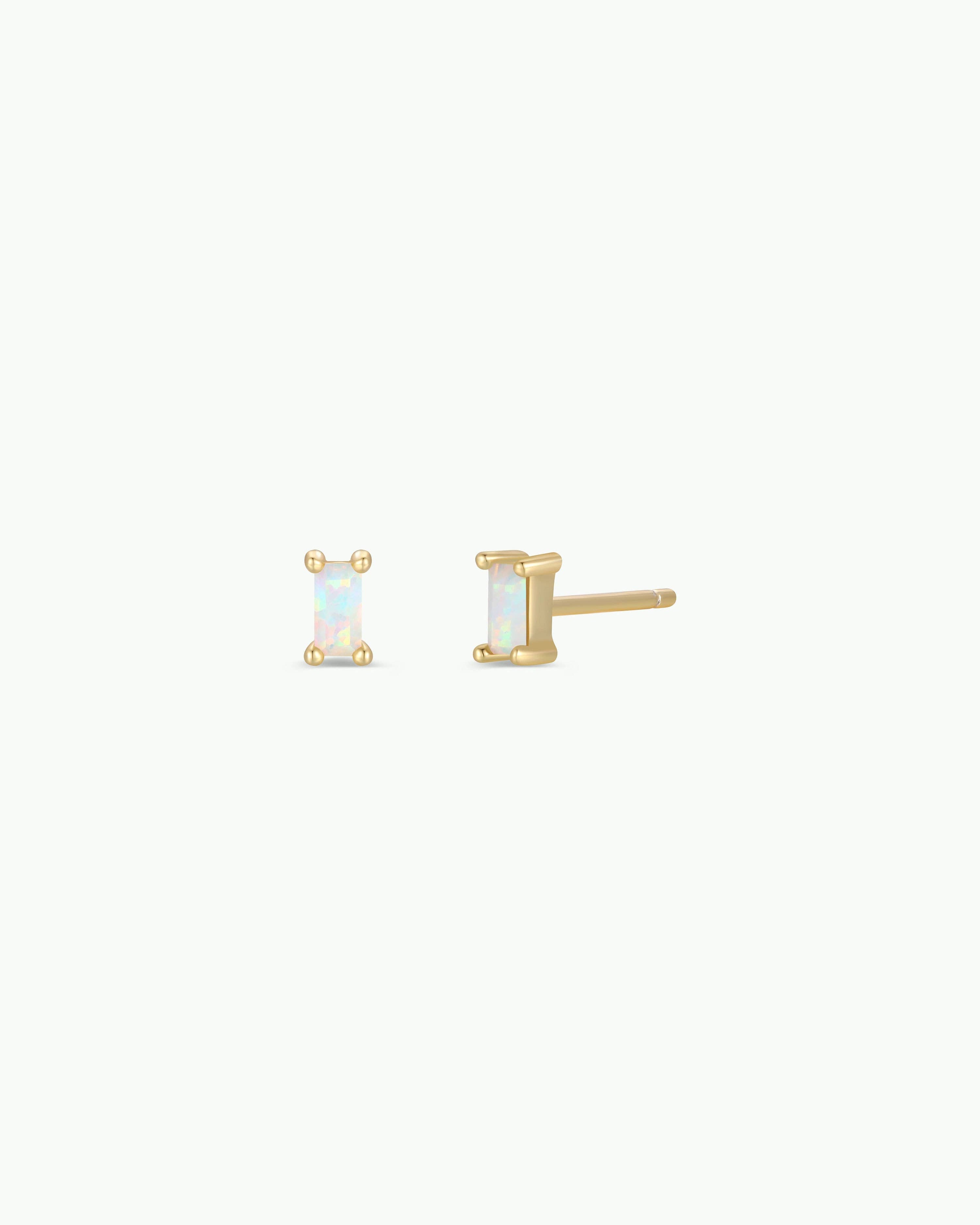 A pair of gold stud earrings with rectangular iridescent opal-like stones, shown on a plain off-white background.