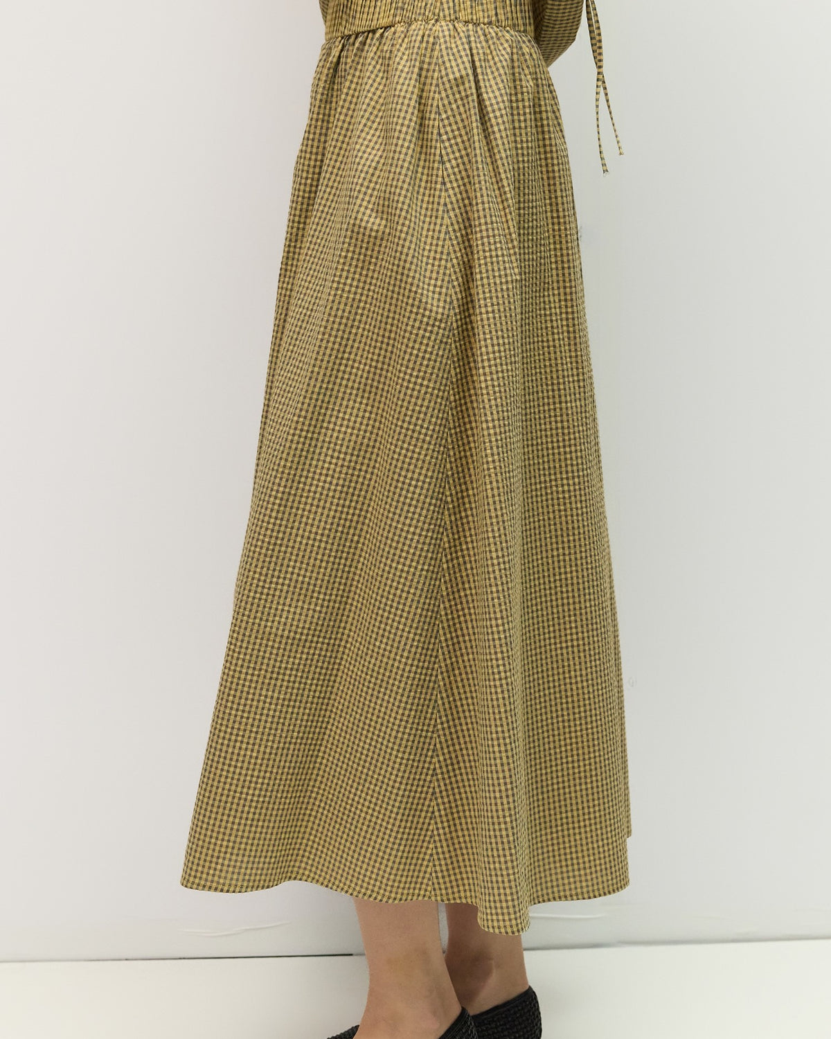 Person wearing a long green checkered skirt on a white background