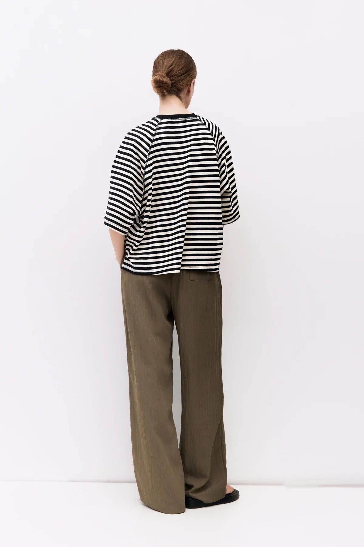 Person wearing a black and white striped shirt and brown pants on a white background