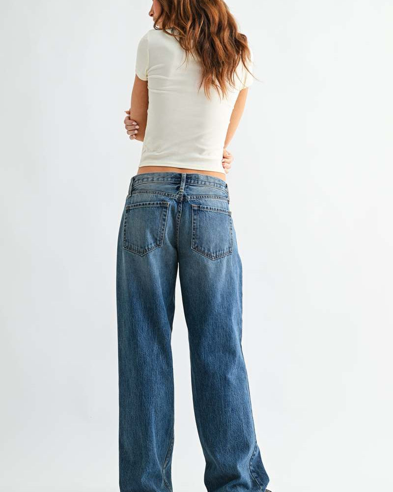 Person wearing blue jeans and a white top on a plain background