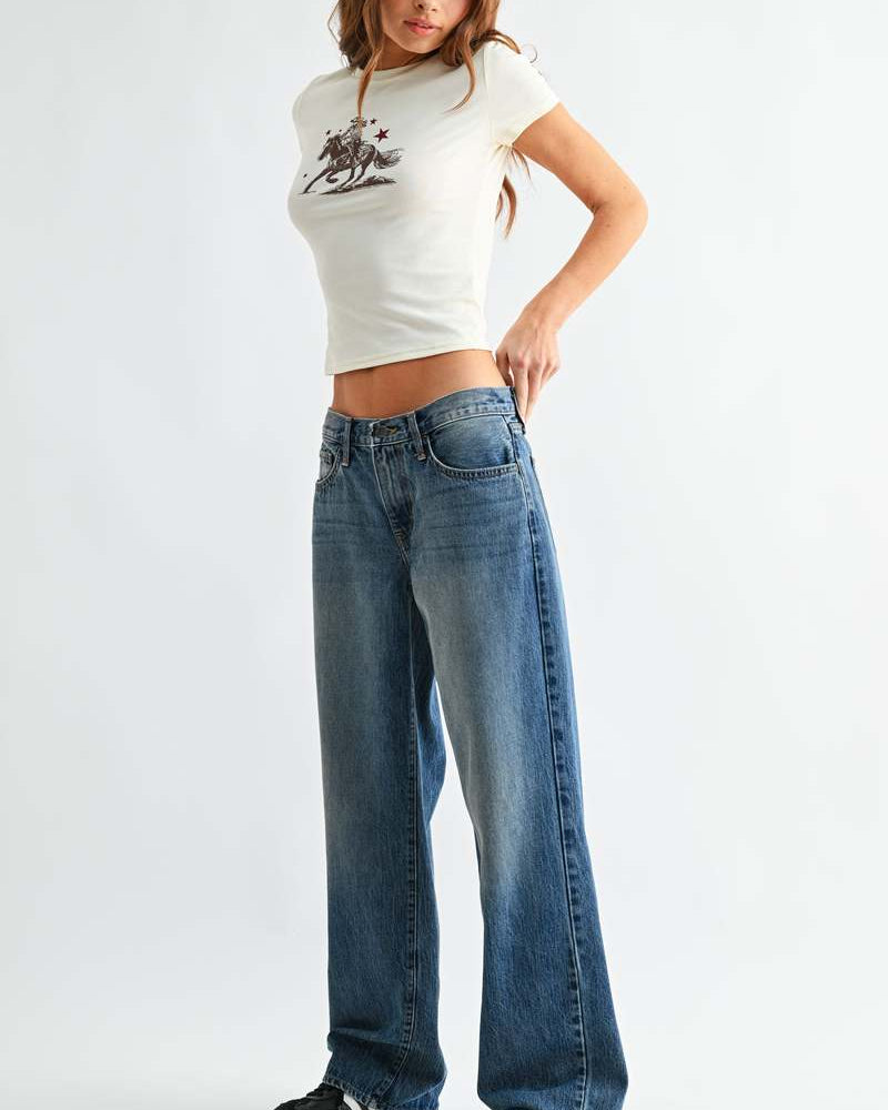 Woman wearing a white crop top with a graphic design and blue jeans on a white background