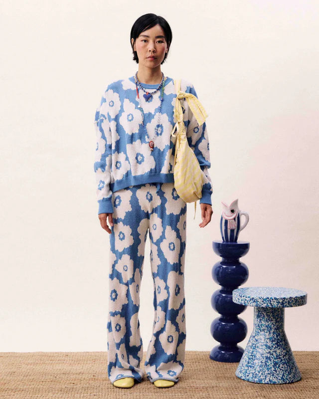 Person wearing a blue floral outfit standing in a room with decorative elements.