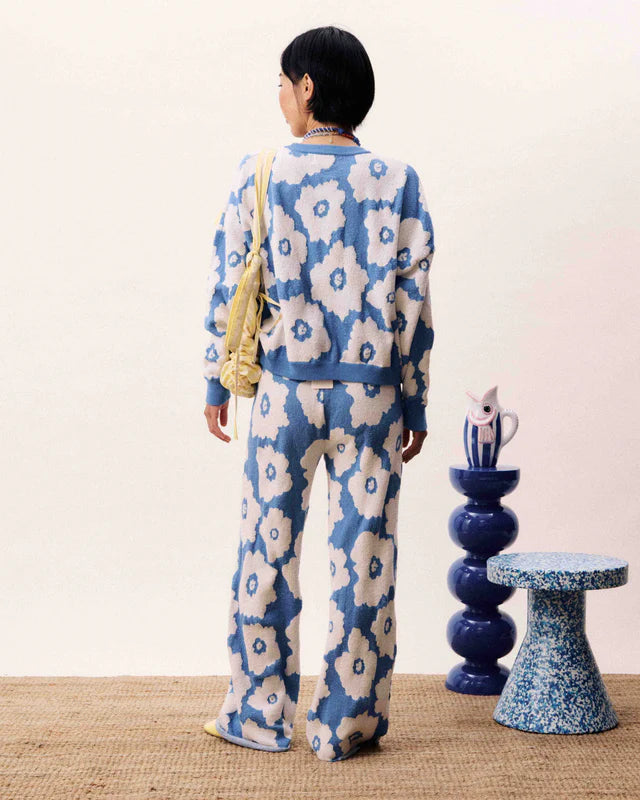Person wearing a blue and white floral patterned outfit standing in a room with decorative elements.