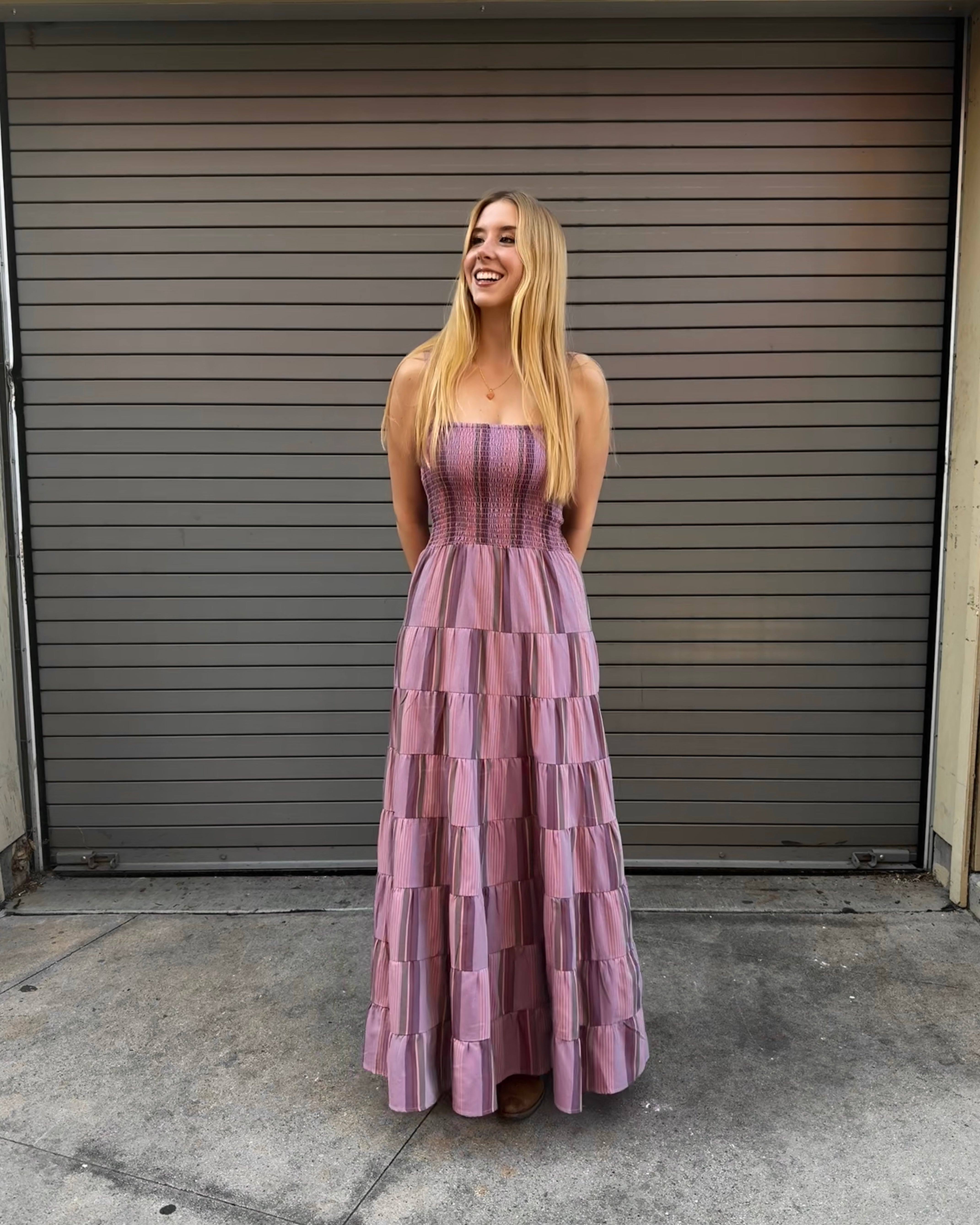 Woman in a purple tiered dress standing in front of a closed garage door.