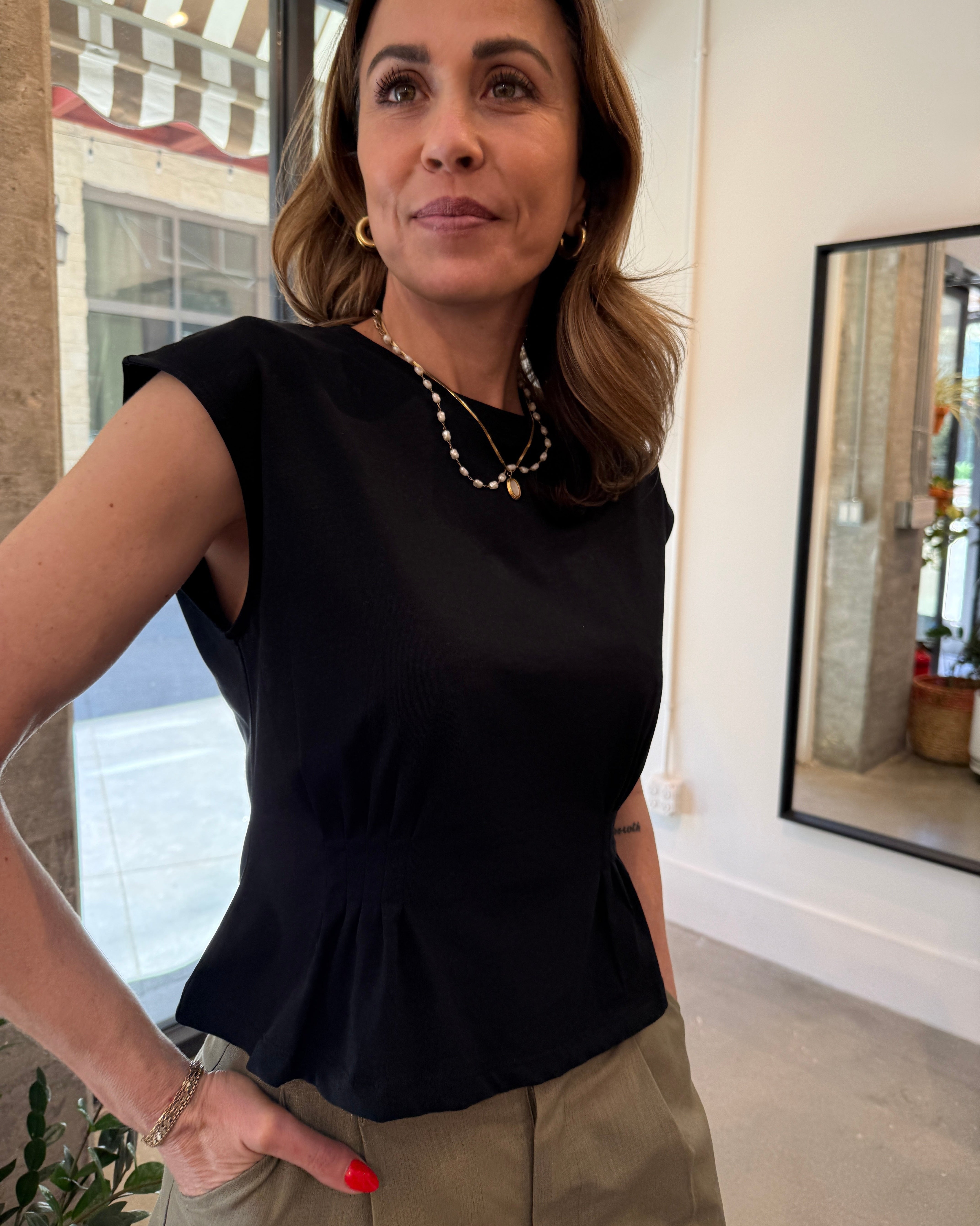 Woman wearing a black top and beige pants in an indoor setting