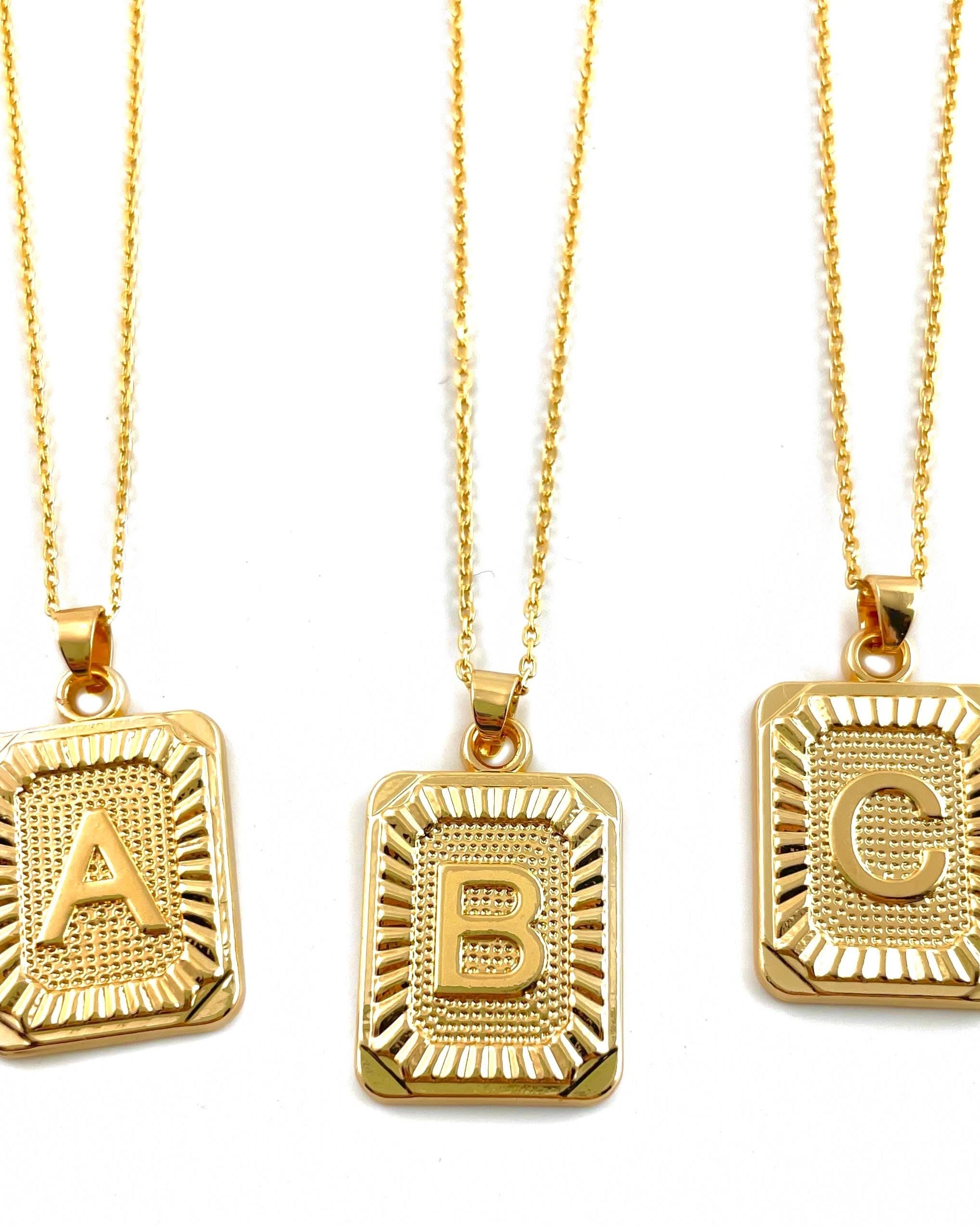 Letter A, B, and C tarnish free gold initial charm necklaces behind a blank background.